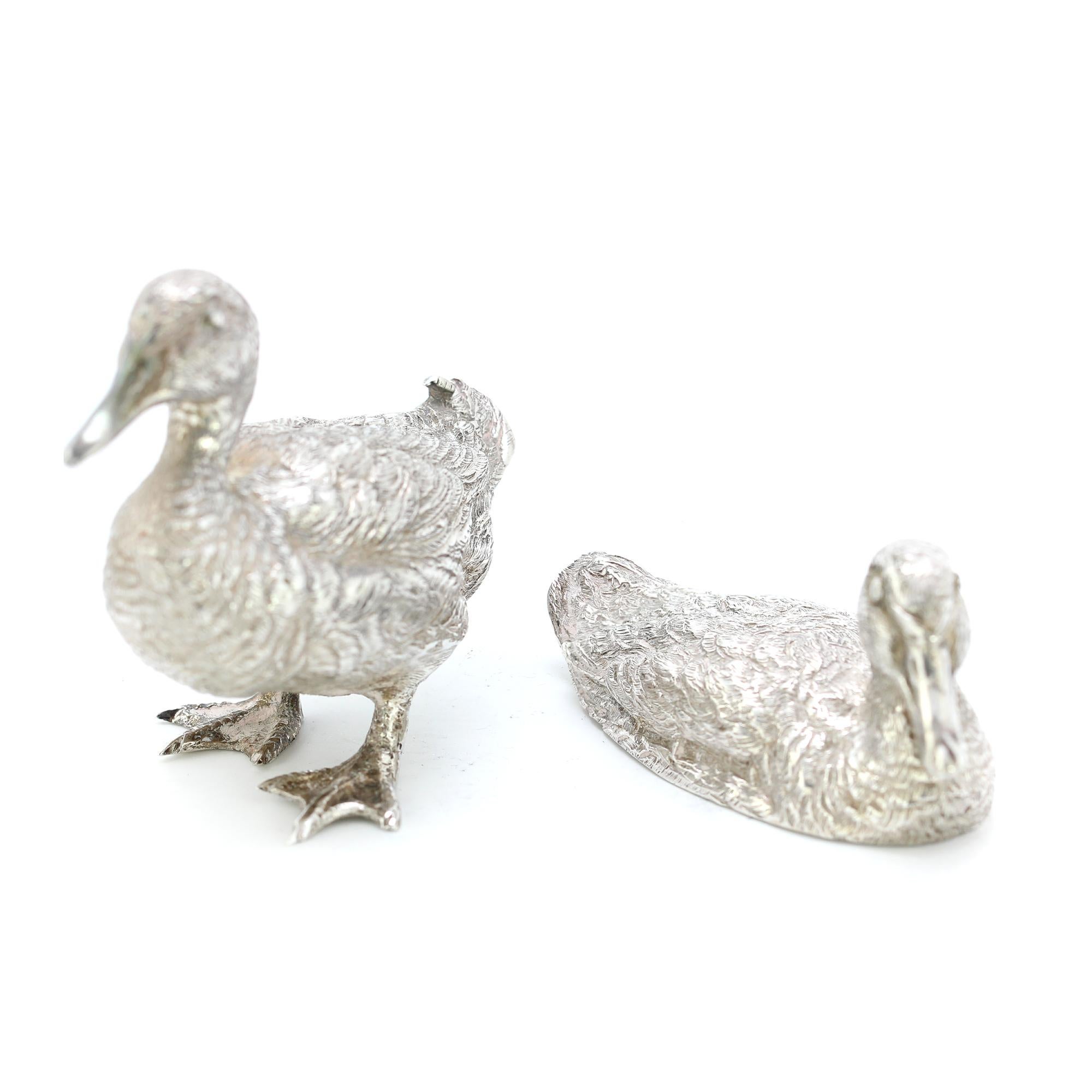 Sterling silver detailed pair of duck figurines
Maker: C F Hancock & Co
Made in London 1973
Fully hallmarked.

Dimensions - 
Size 1 standing duck: 6.5 x 3.2 x 5.5 cm
Size 2 sitting duck: 6.7 x 2.7 x 3 cm
Weight : 159 grams