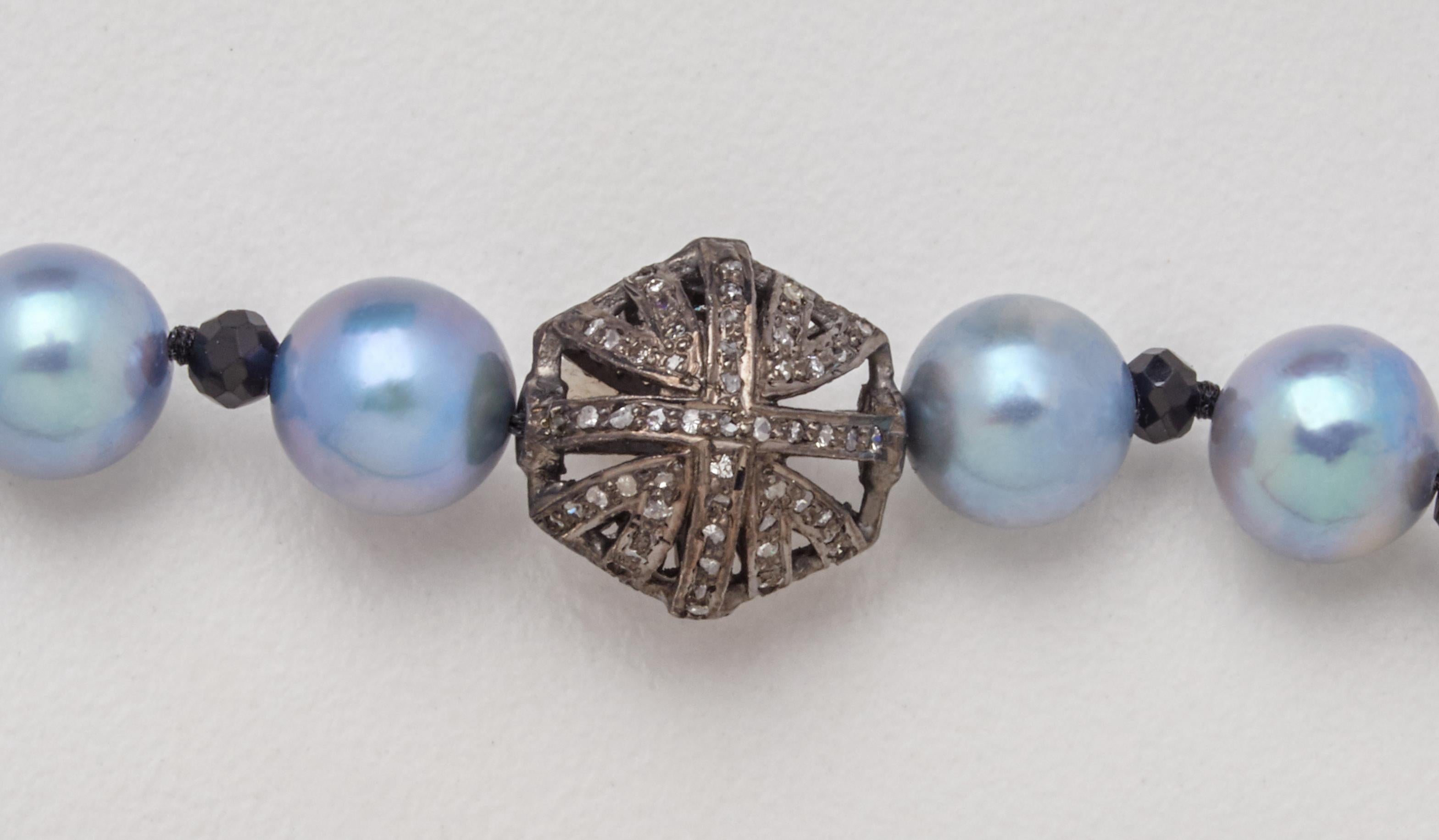 Sixteen soft powder blue colored 7.5mm Akoya pearls hand-stung and off-set with black spinel beads create this very versatile look that can go from dress to jeans. The featured oxidized silver and diamond puff charm and decorative clasp give sparkle