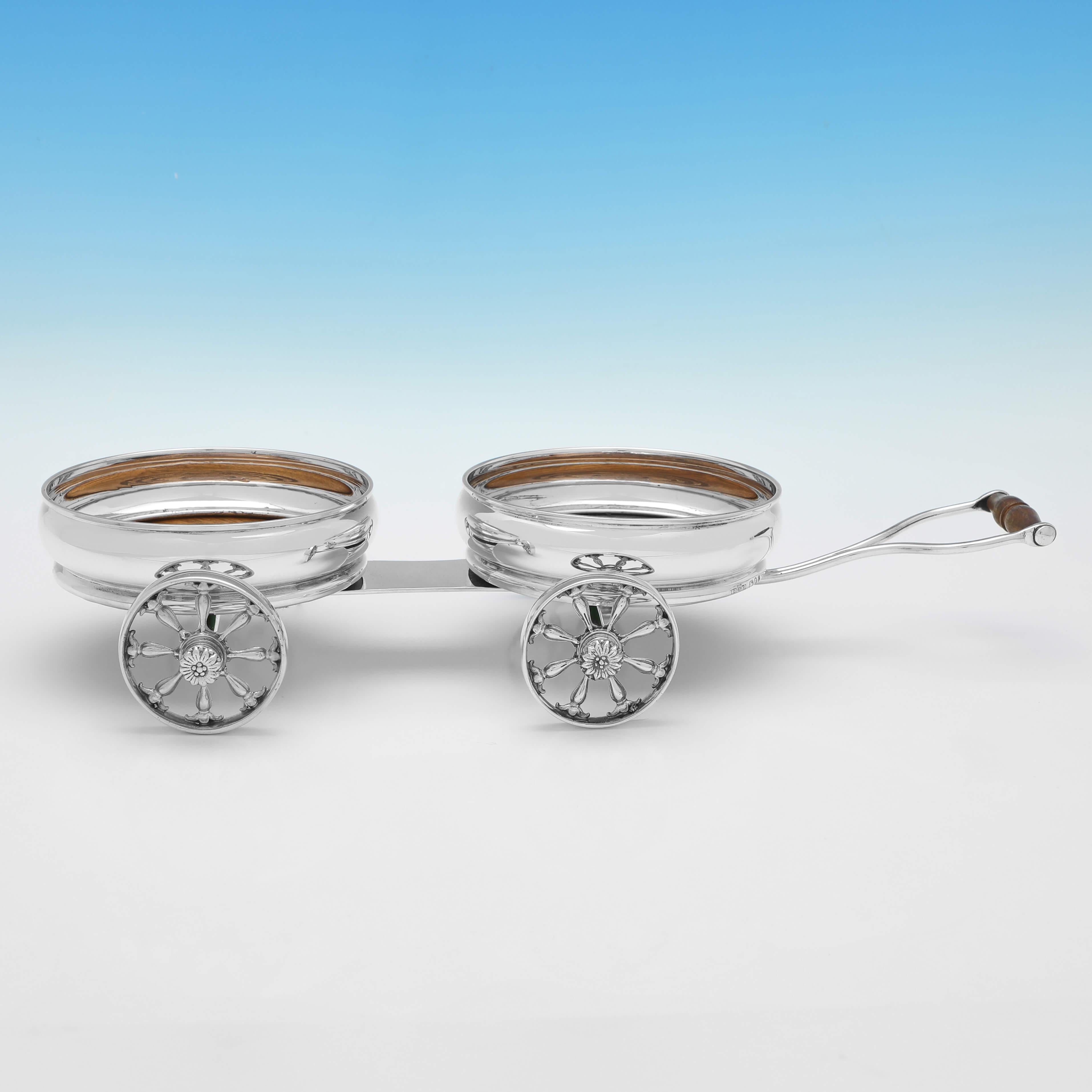 Hallmarked in London in 1970 by S. M. Shaw, this very stylish and rare, Sterling Silver Double Wine Coaster Trolley, is plain in design, with turned wooden bases to the coasters. 

The wine coaster trolley measures 3