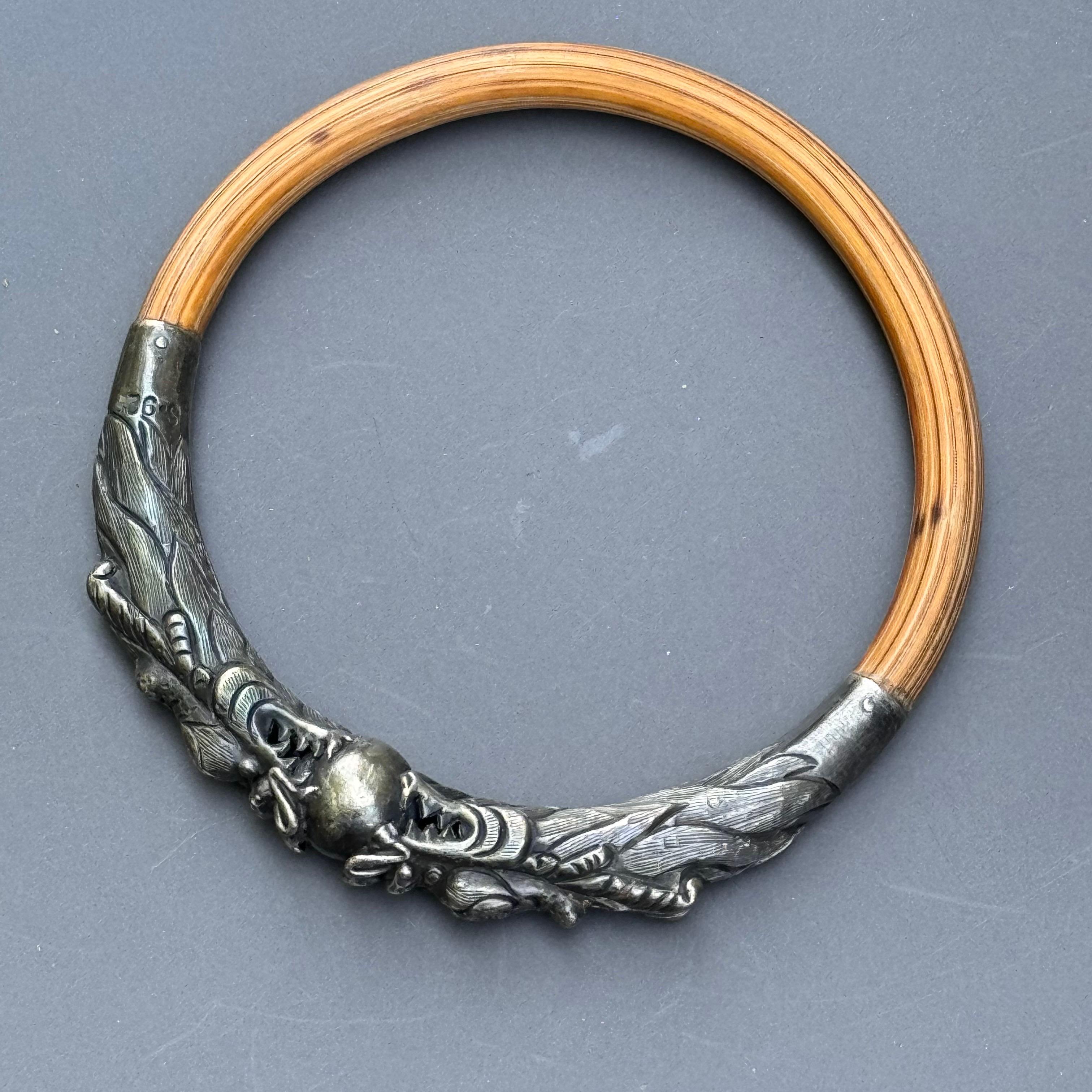 Dieser exquisite Armreif aus antikem chinesischem Silber besticht durch sein kunstvolles Design aus Rattan-Bambus und doppelköpfigen Drachen, die eine Weltkugel halten. Die detaillierten Schnitzereien, darunter fein gearbeitete Drachenzähne, zeugen