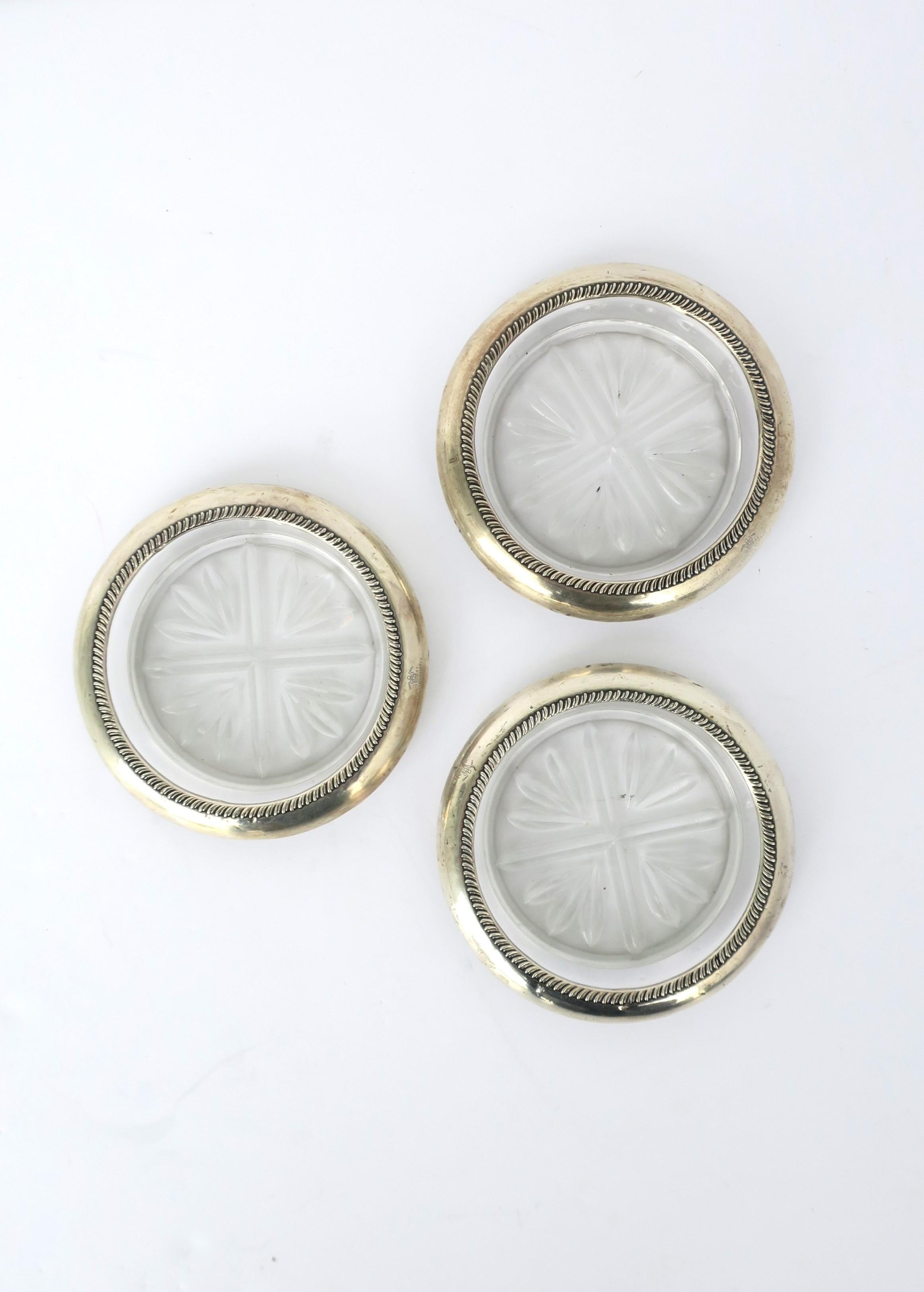 A set of three (3) sterling silver and cut-glass coaster set, circa early to mid-20th century, USA. Three coasters with sterling silver overlay and cut-glass design on bottom. Essential for protecting furniture tops. Each marked 'FB Rogers Silver