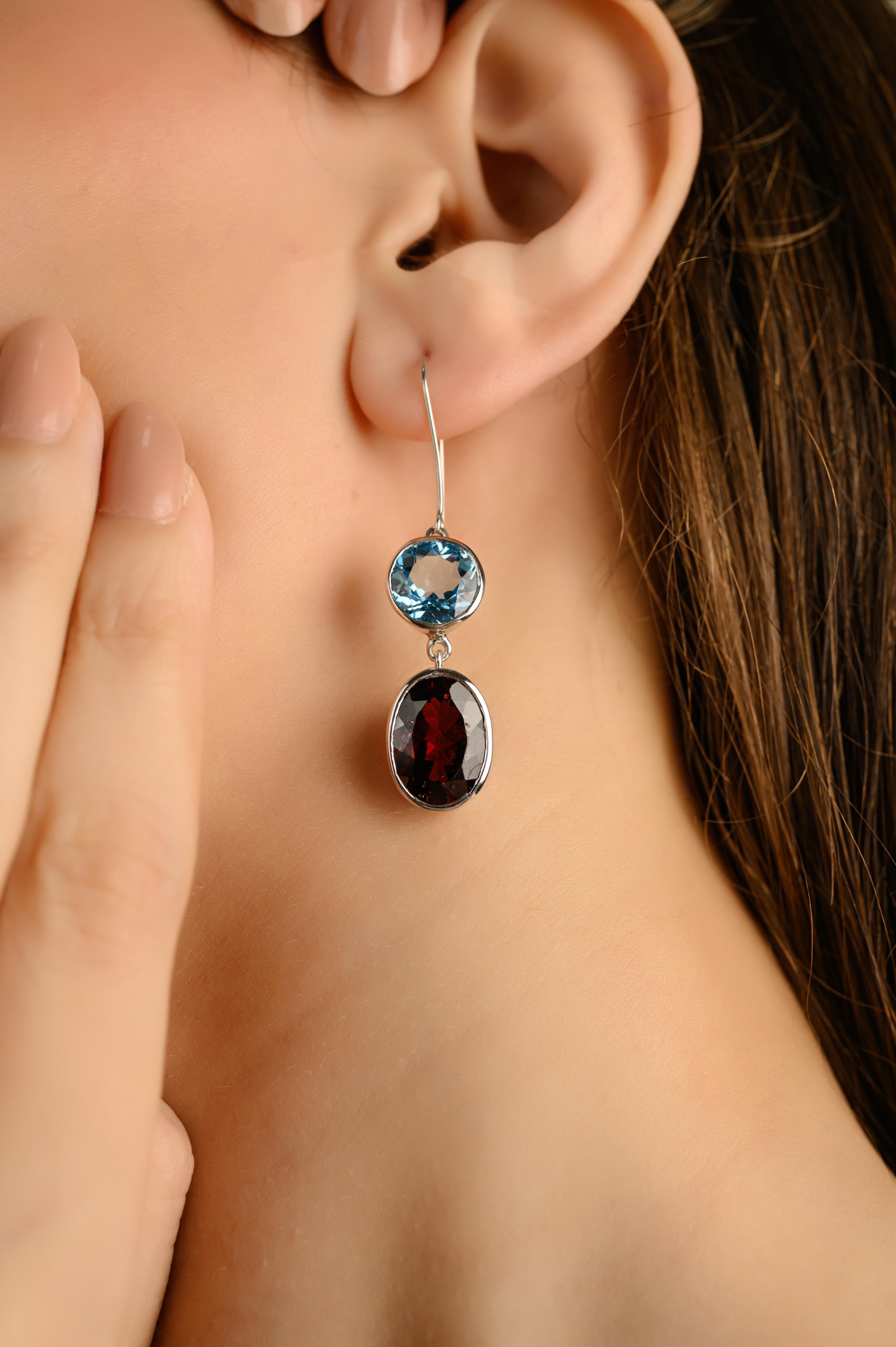 Questi orecchini a goccia in argento sterling con gemme di topazio blu e granato, realizzati a mano, sono caratterizzati da una straordinaria combinazione di colori e forme. Incastonato in argento sterling 925, ogni orecchino presenta un vibrante