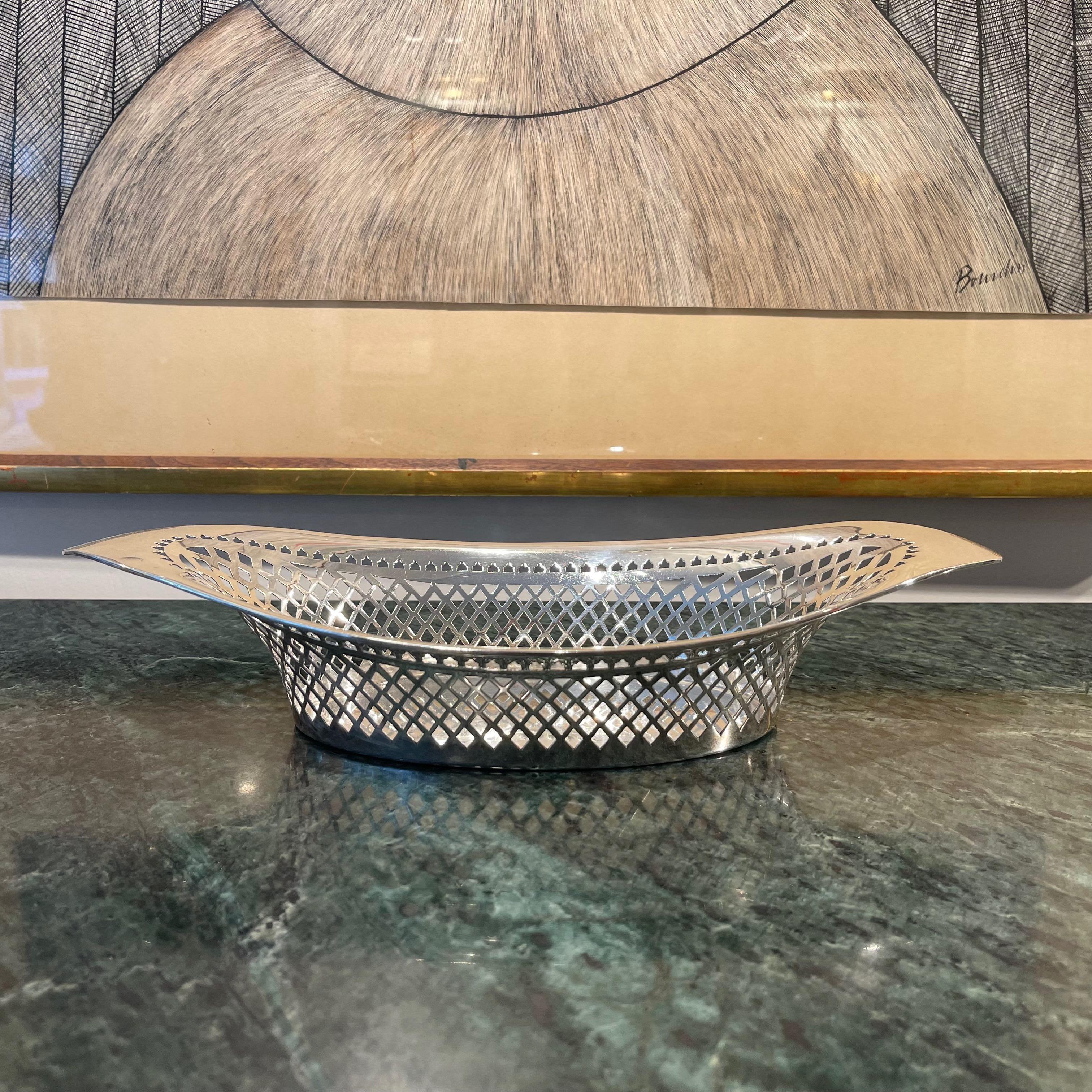A beautiful geometric grid of diamonds and triangles are cut out symmetrically from the sides of this solid sterling silver Edwardian breadbasket. Above this, a line of small trefoil arches leads into a wide rim bearing the hallmark of the Atkin