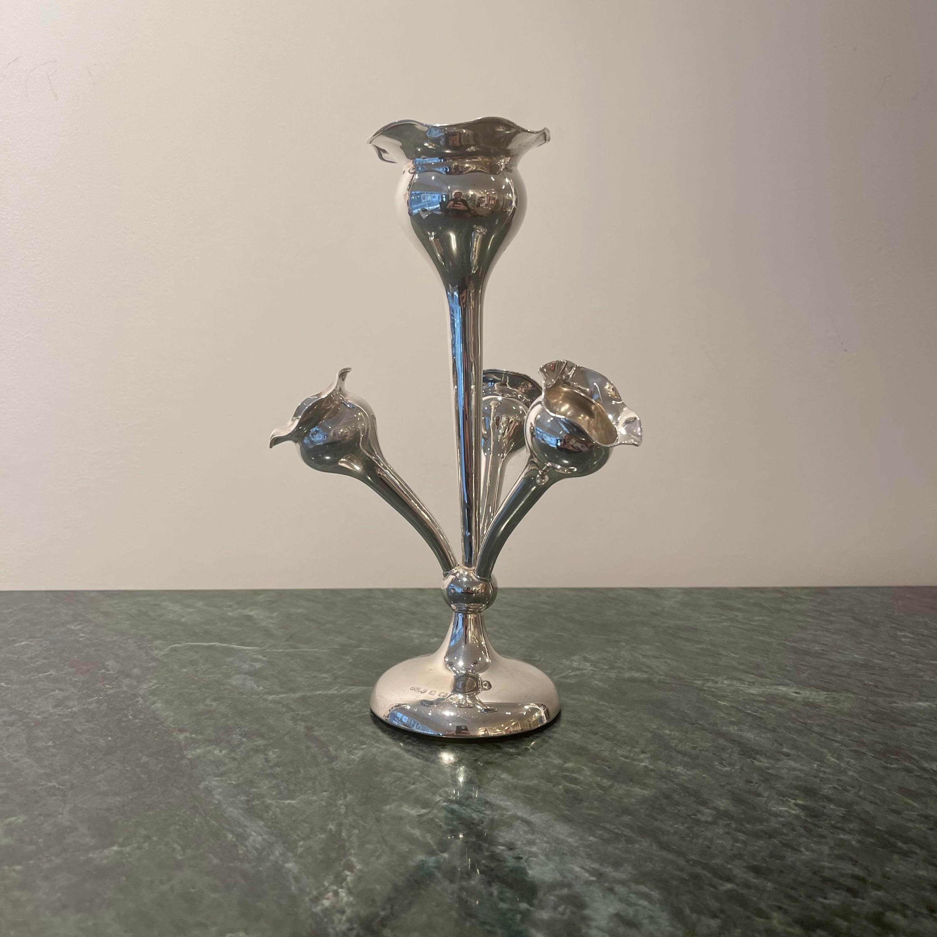 Characteristic of the centrepieces known as Epergnes, this medium-sized Sterling Silver Edwardian example is designed to display flowers in its blooming-lipped central trumpet vase and and three smaller radiating branches. The central stem is fixed,