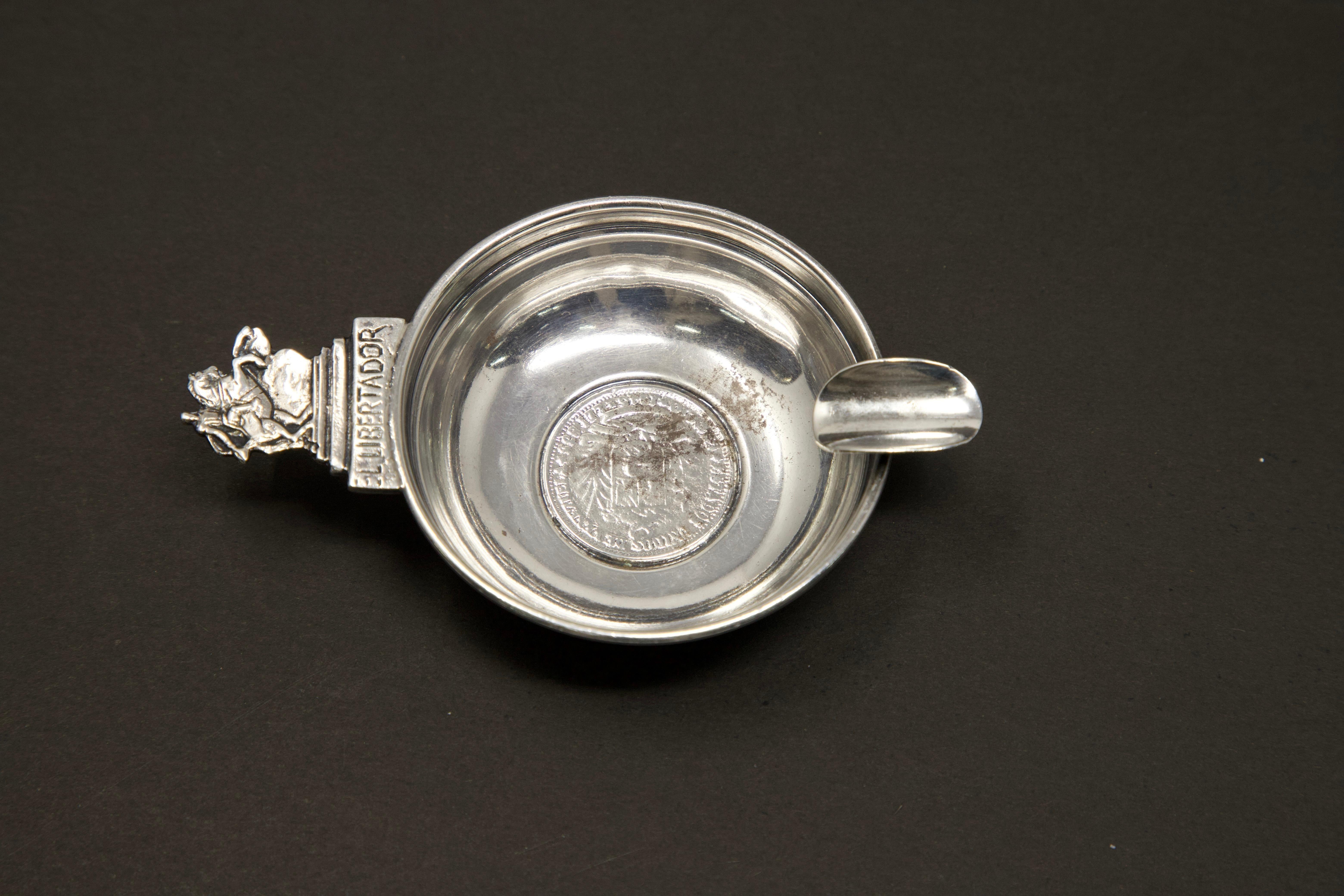 Offering this beautiful sterling silver El Libertador wine taster. The coin is hard to make out the interior however the back of the coin is marked Bolivar Libertador and it is from Venezuela. The handle is a man riding a horse and underneath is