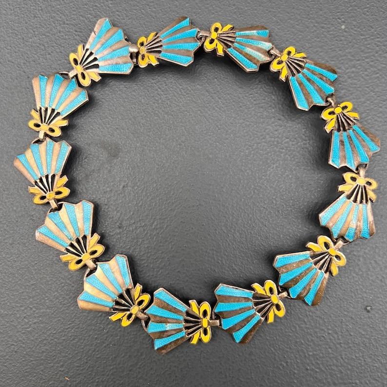 This beautifully crafted vintage collar necklace from Taxco, Mexico, is a striking example of mid-20th-century Mexican silversmithing. Made from sterling silver with fan-shaped enamel links, the necklace is signed by the renowned artisan M. Arins
