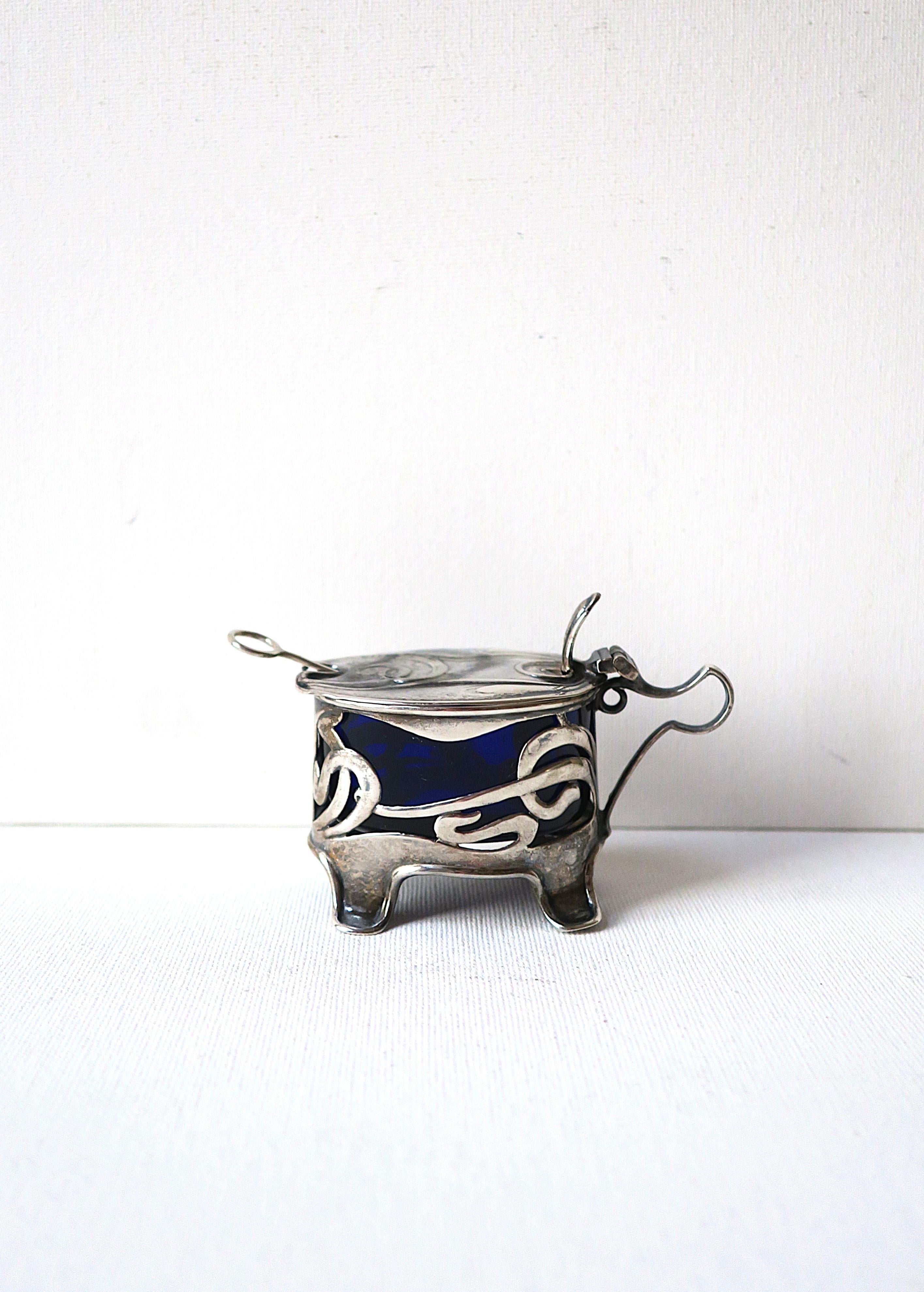 A beautiful English sterling silver salt cellar, Art Nouveau period, circa early-20th century, England. Cellar or vessel has oval sapphire blue glass insert along with a sterling silver spoon (and crystal spoon.) With English markers' mark and