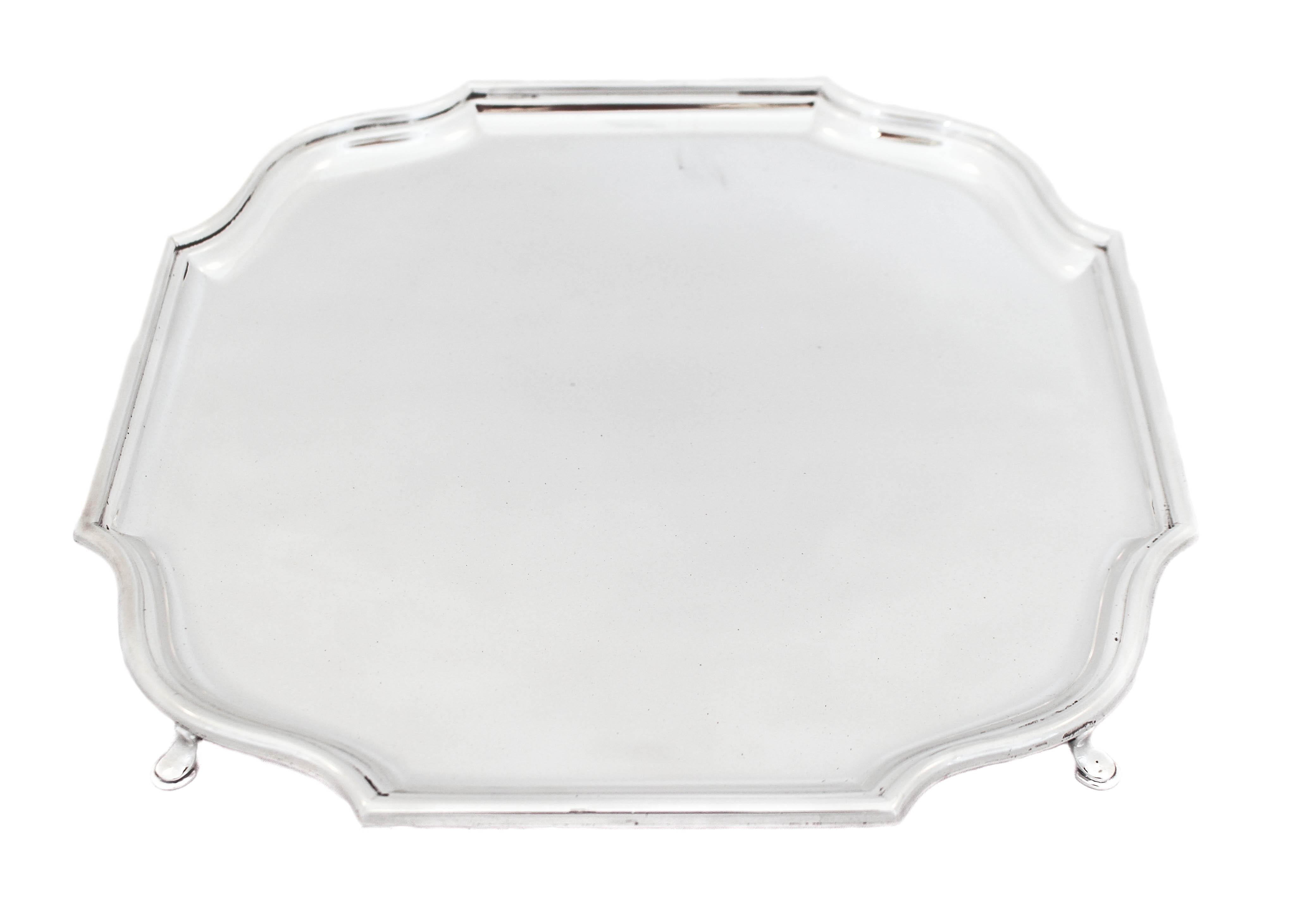 This sterling silver salver was manufactured in 1933 by Hawksworth, Eyre & Company of Birmingham, England. It is quintessential English with its simplicity and straight lines. Standing on four feet it is raised off the surface. The rim is scalloped