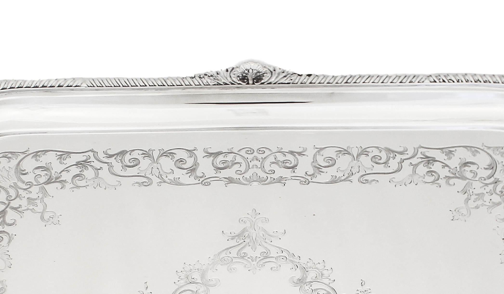 Being offered is an exceptionally large and heavy sterling silver (tea)tray by Atkin Brothers of Sheffield, England— hallmarked 1903. 
It has a gadroon design around the rim intercepted by a shell design on each side and corner.  The entire inside