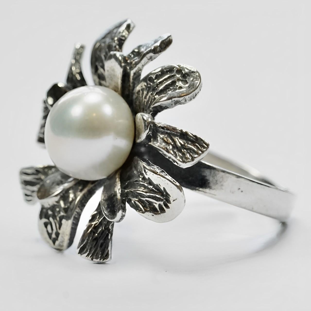 Beautiful sterling silver flower ring with engraved and shiny petals and featuring a cultured pearl. Ring size UK I, US 4 1/4, inside diameter 1.6 cm / .6 inch.

This is a stylish and unusual silver and pearl ring, handmade in Tiznit, Morocco. 