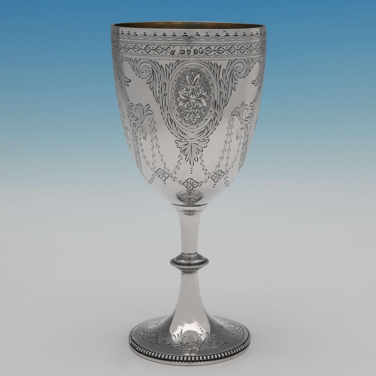 Hallmarked in London in 1886 by Charles Stuart Harris, this attractive, Victorian, antique sterling silver goblet, features attractive bright cut engraved decoration to the body and foot, a bead border and gilt interior. 

The goblet is engraved