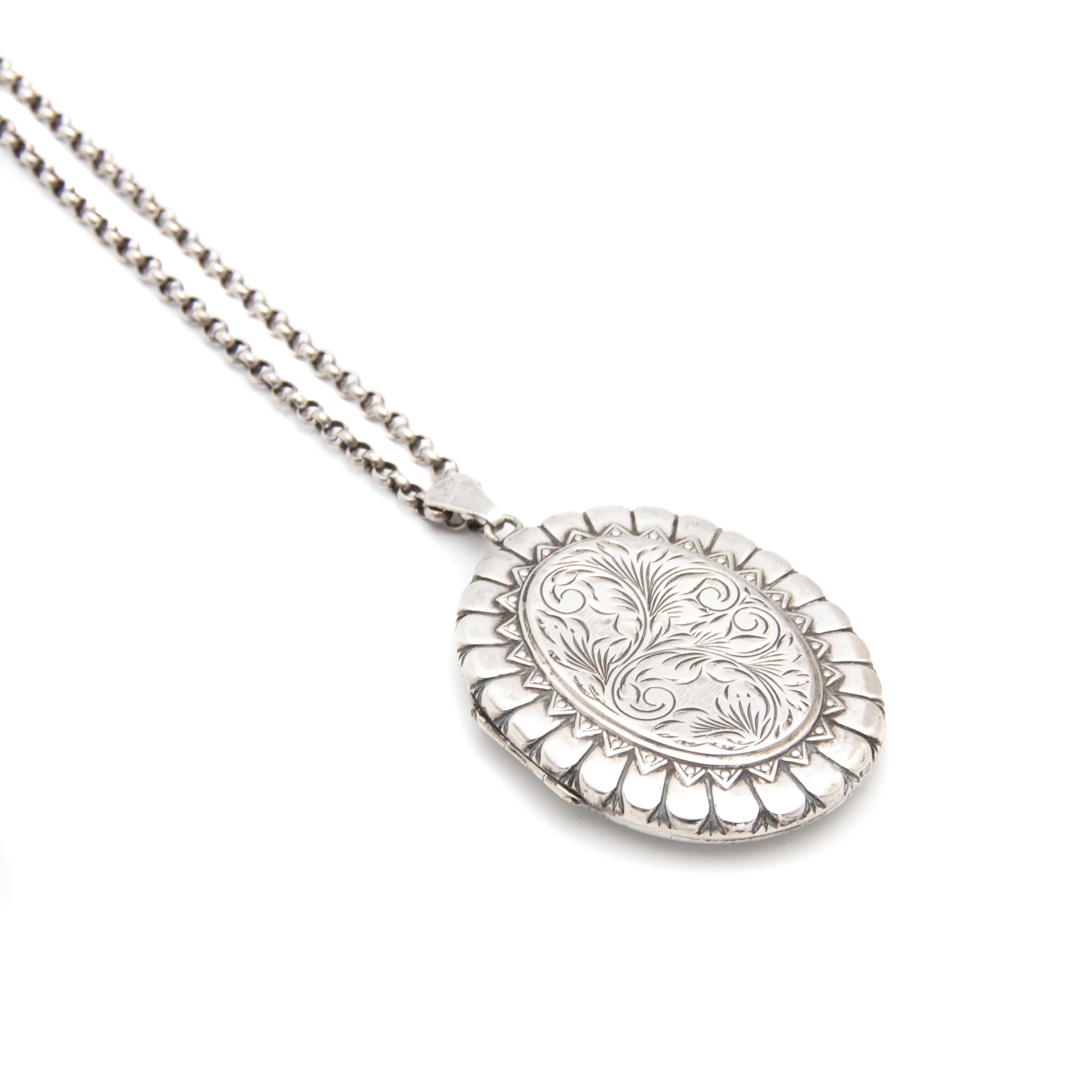 This English silver vintage locket pendant comes with this silver chain. The extra large silver locket has been beautifully hand chased with swirling plumes and the border has an etched design. In the frames you could place photographs of loved