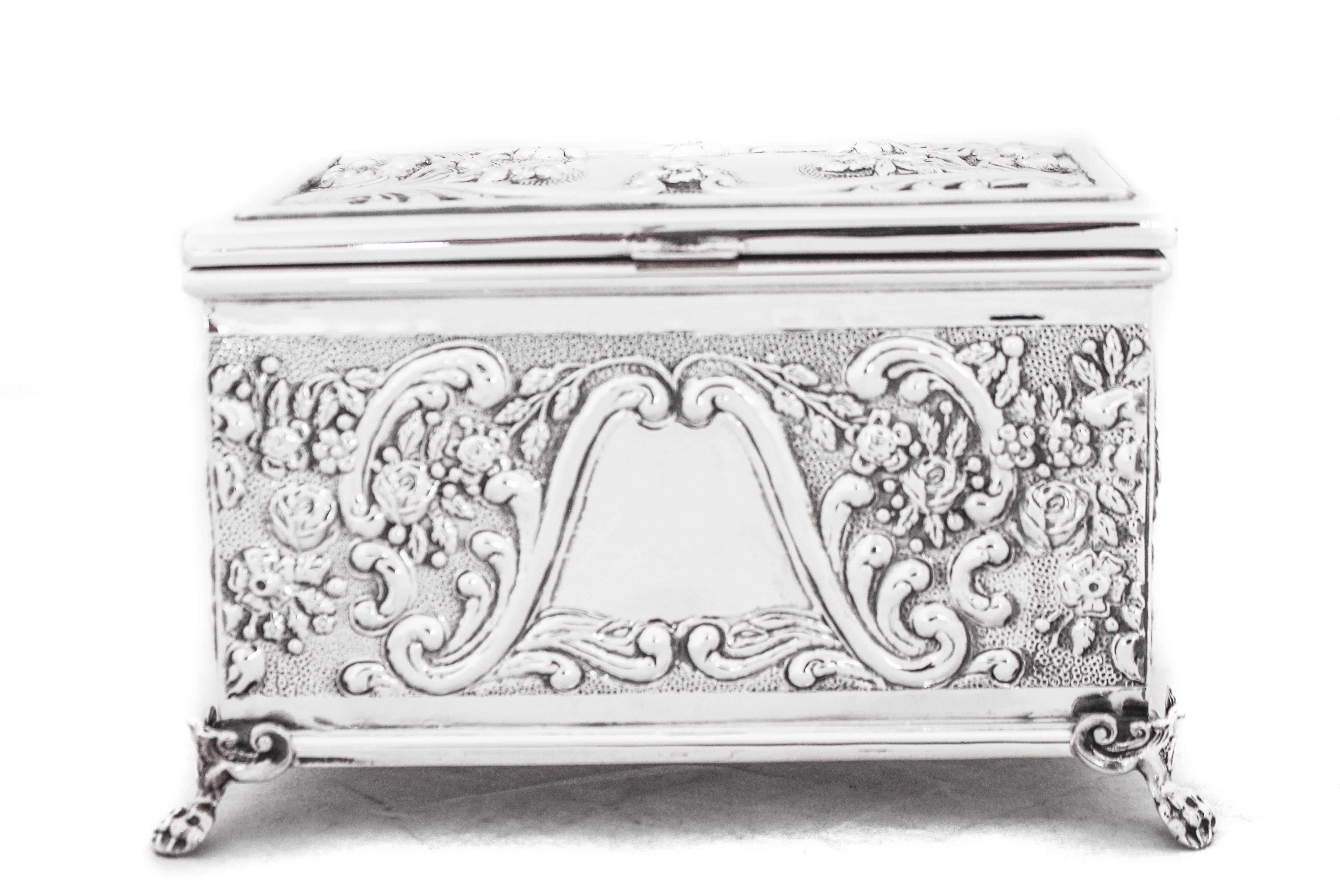 Being offered is a sterling silver Etrog box.  It is rectangular and stands on four feet.  It has raised-work of flowers, leaves & swirls on the lid as well as on each panel.  The inside is gold washed to protect it.  What a beautiful way to perform