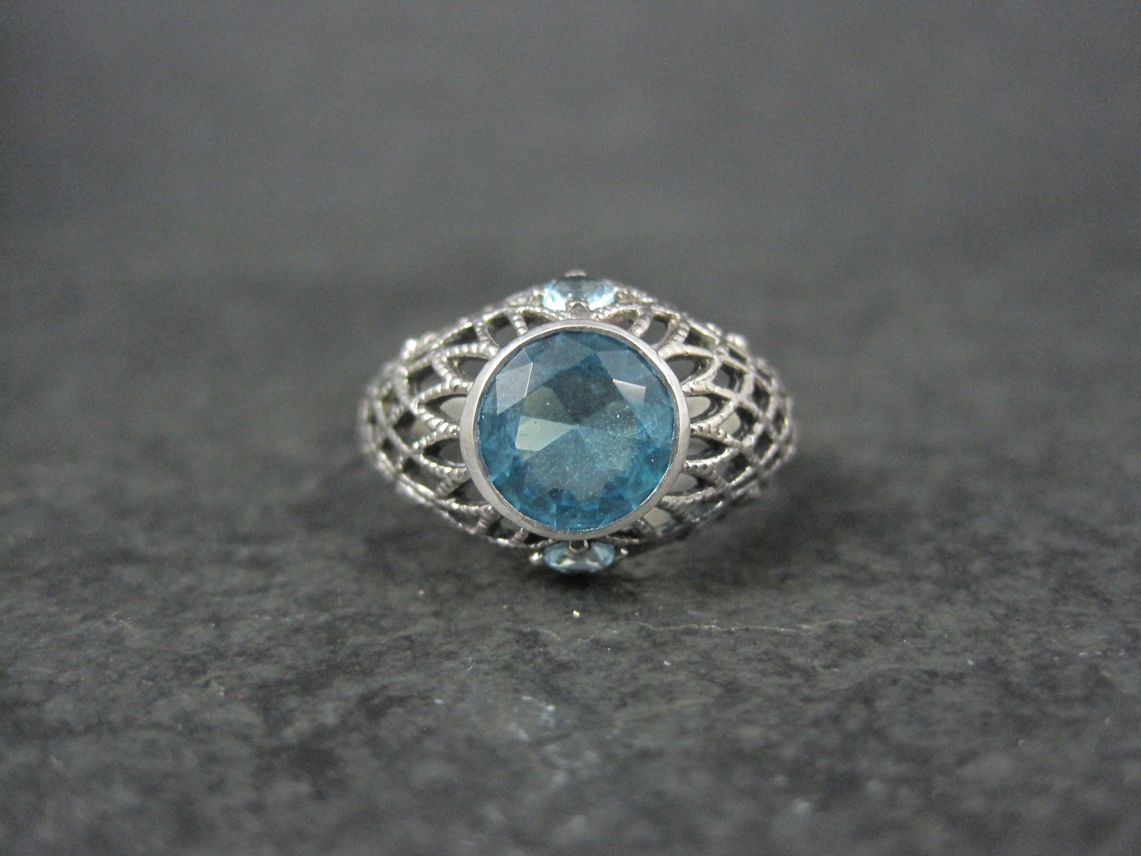This gorgeous ring is sterling silver with delicate, floral filigree. 
It is a modern ring made from original art deco molds. 
It features 8mm and 3mm round blue tourmaline gemstones.
The face of this ring measures 1/2 of an inch north to south with
