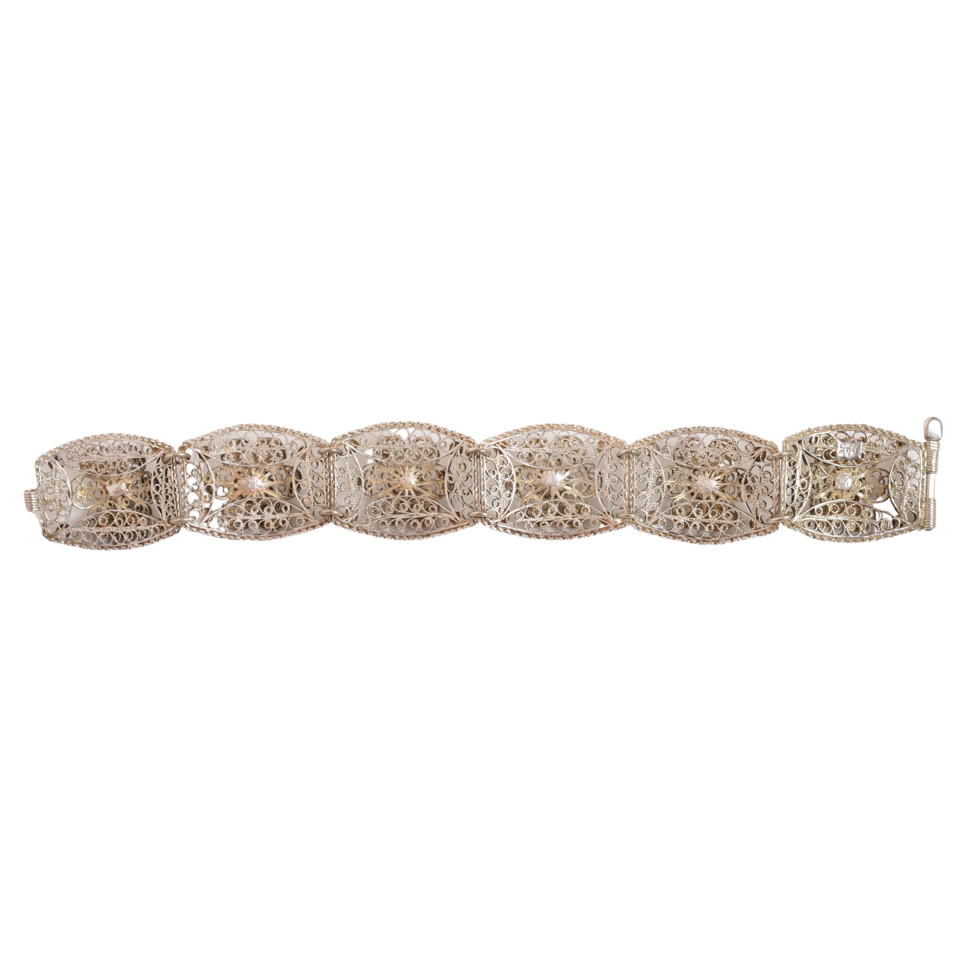 Filigranes Sterlingsilberarmband um 1940. Silbernes Gliederarmband mit sechs filigranen Blumen. Die tonneauförmigen, gewölbten floralen Medaillons sind jeweils 29 mm lang und 23 mm breit. Der Stiftverschluss funktioniert gut und bleibt auch beim