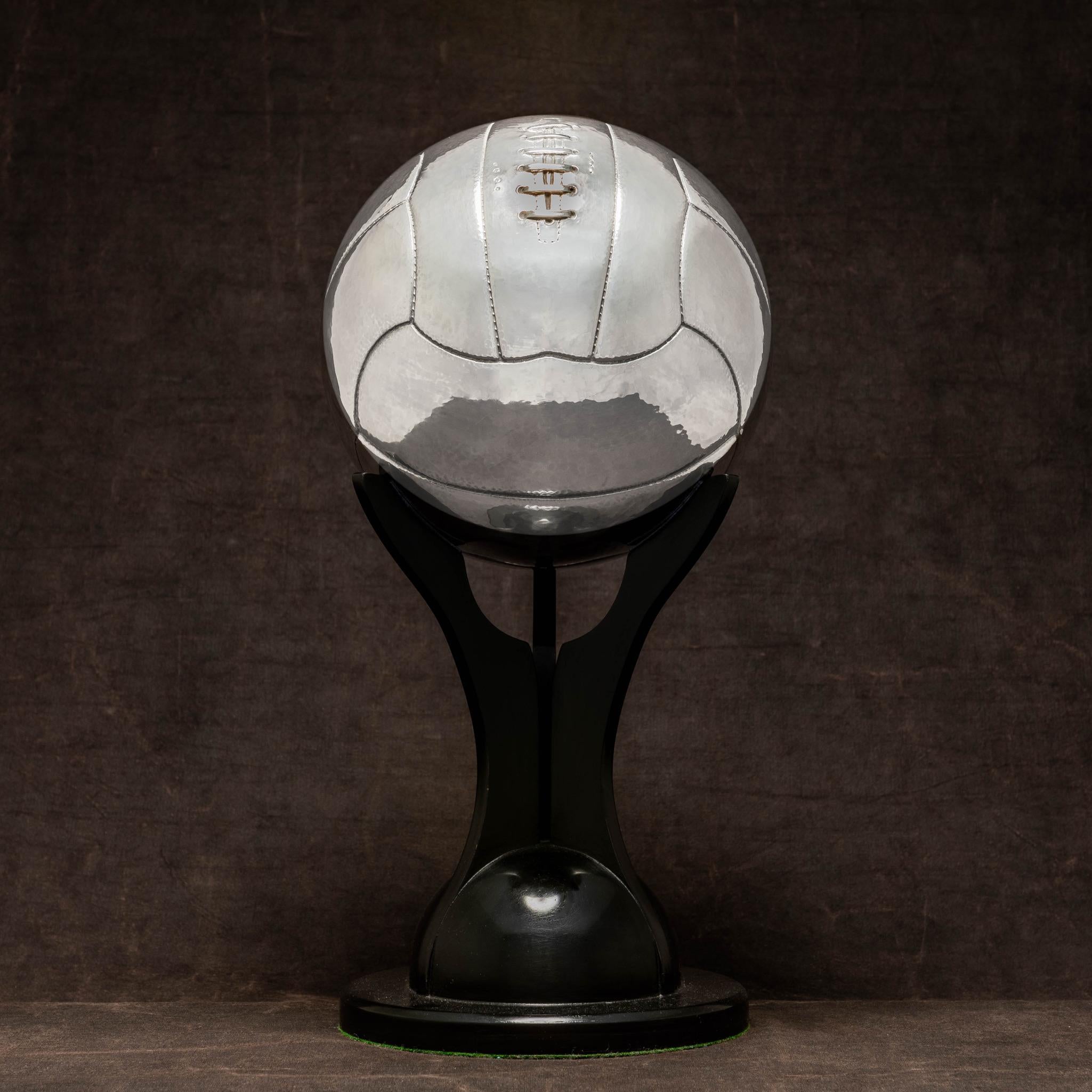 An exceptional life-size sterling silver football with gently hammered surface and skilfully detailed lacing. The ball is very tactile and we have made a bespoke ebonised stand so that the ball can easily be removed and handled. With silver marks