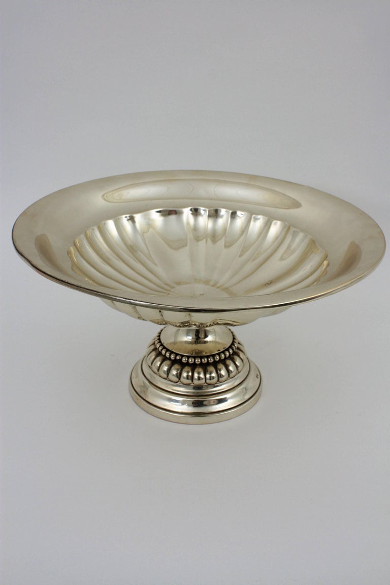 Elegant neoclassical style Tazza centerpiece, sterling silver. Spain, 1950s.
This exceptional spanish sterling silver bowl has a circular shaped form onto a spreading foot.
Measures: Height: 19 cm
Diameter: 36 cm
Stamps: Star - 925 
Weight: