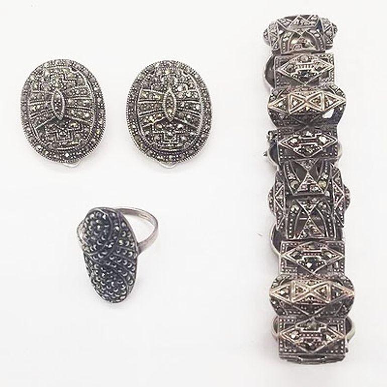 This Mid-Century and Art Deco Estate Jewelry Marcasite Set is a dazzling ensemble featuring a brooch, bracelet, and clip-on earrings. Crafted with intricate marcasite detailing set in timeless designs, this set exudes elegance and vintage charm,