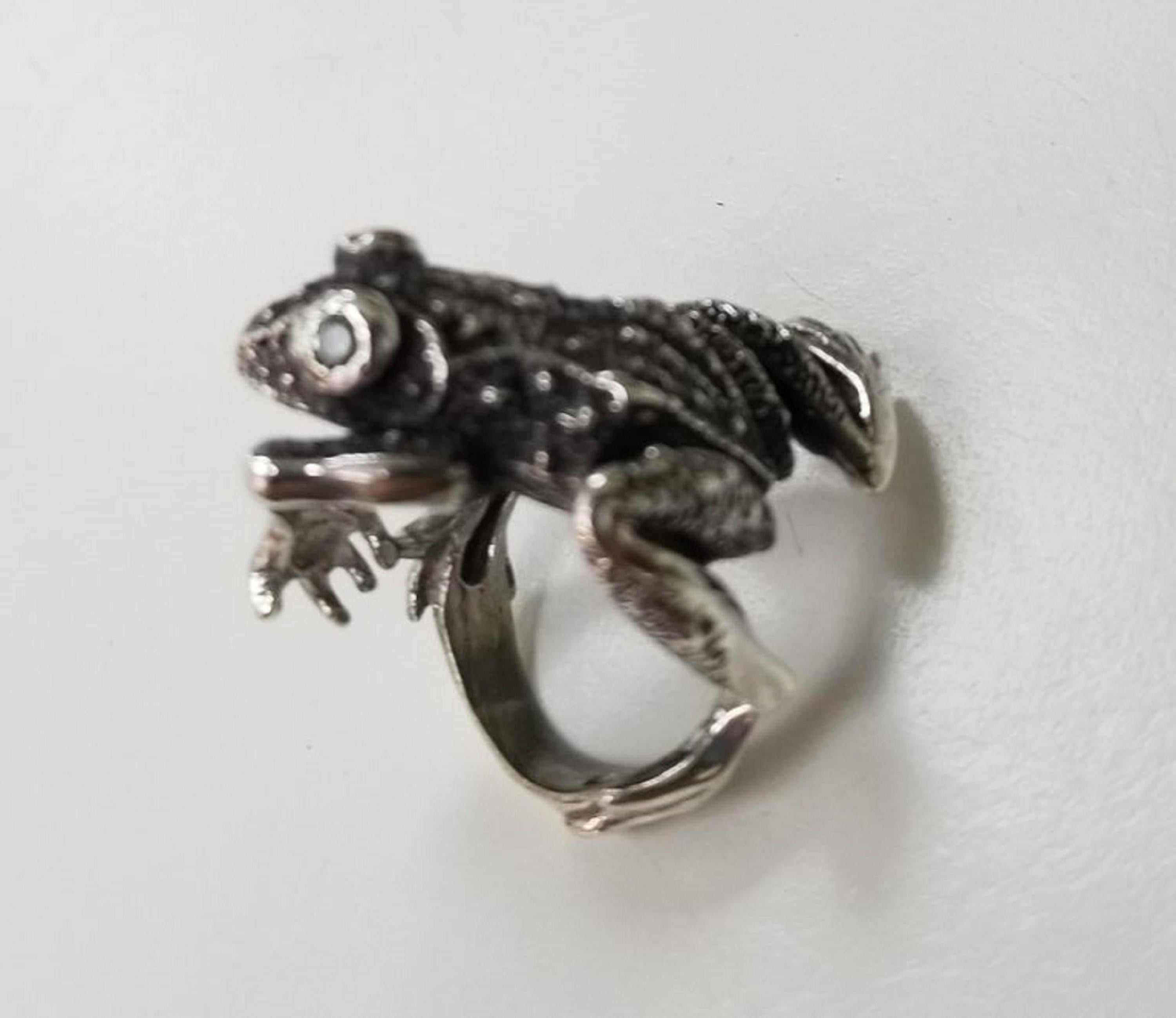 Sterling silver frog with green sapphire as eyes weighing .24pts., the ring is a size 6, with black antiquing to show highlights.