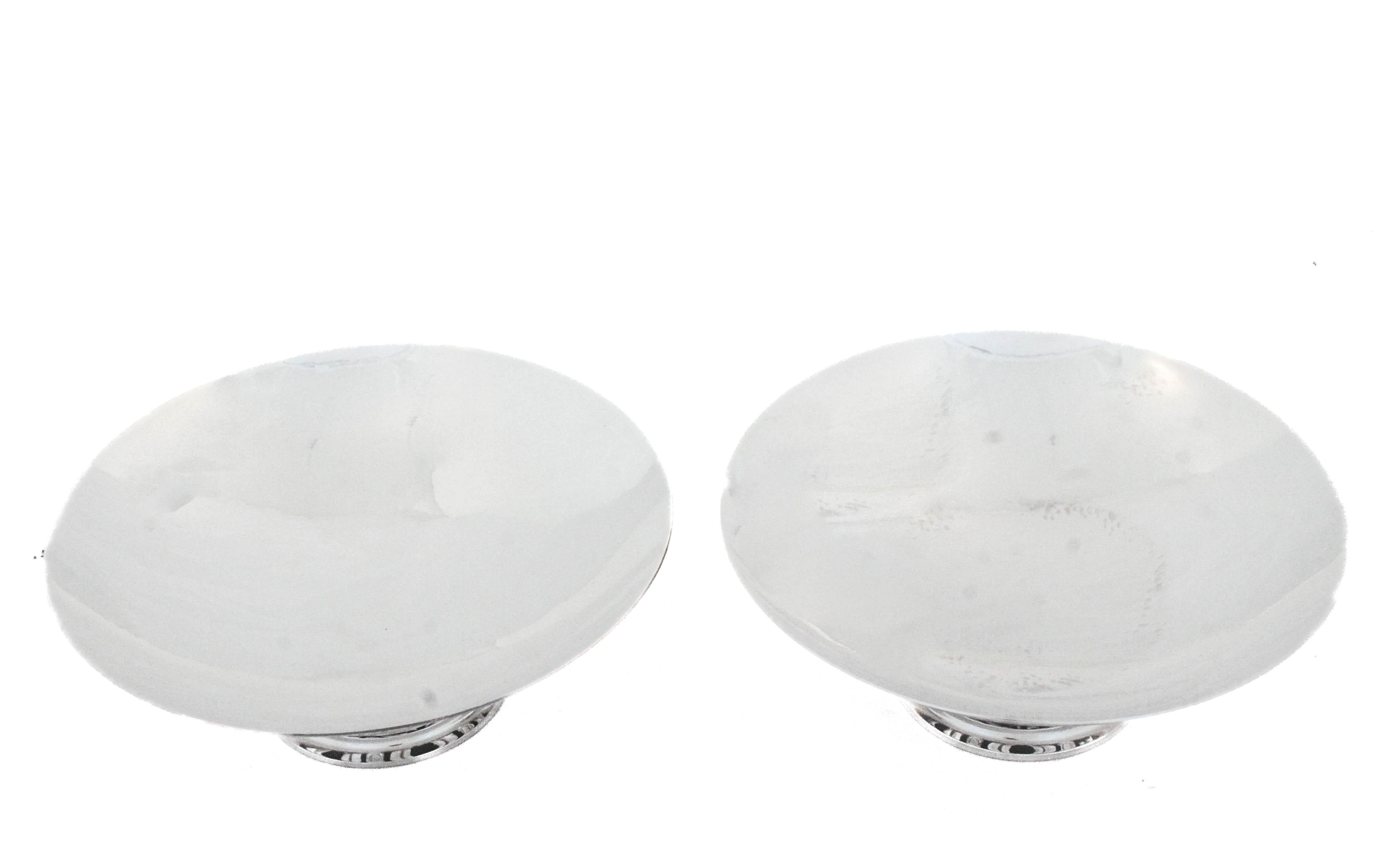 Sono entusiasta di offrire questa coppia di composte in argento sterling di Georg Jensen, in Danimarca.  La parte superiore è una ciotola piuttosto che una superficie piatta, quindi può contenere qualsiasi cosa senza che cada.  Il piedistallo è la