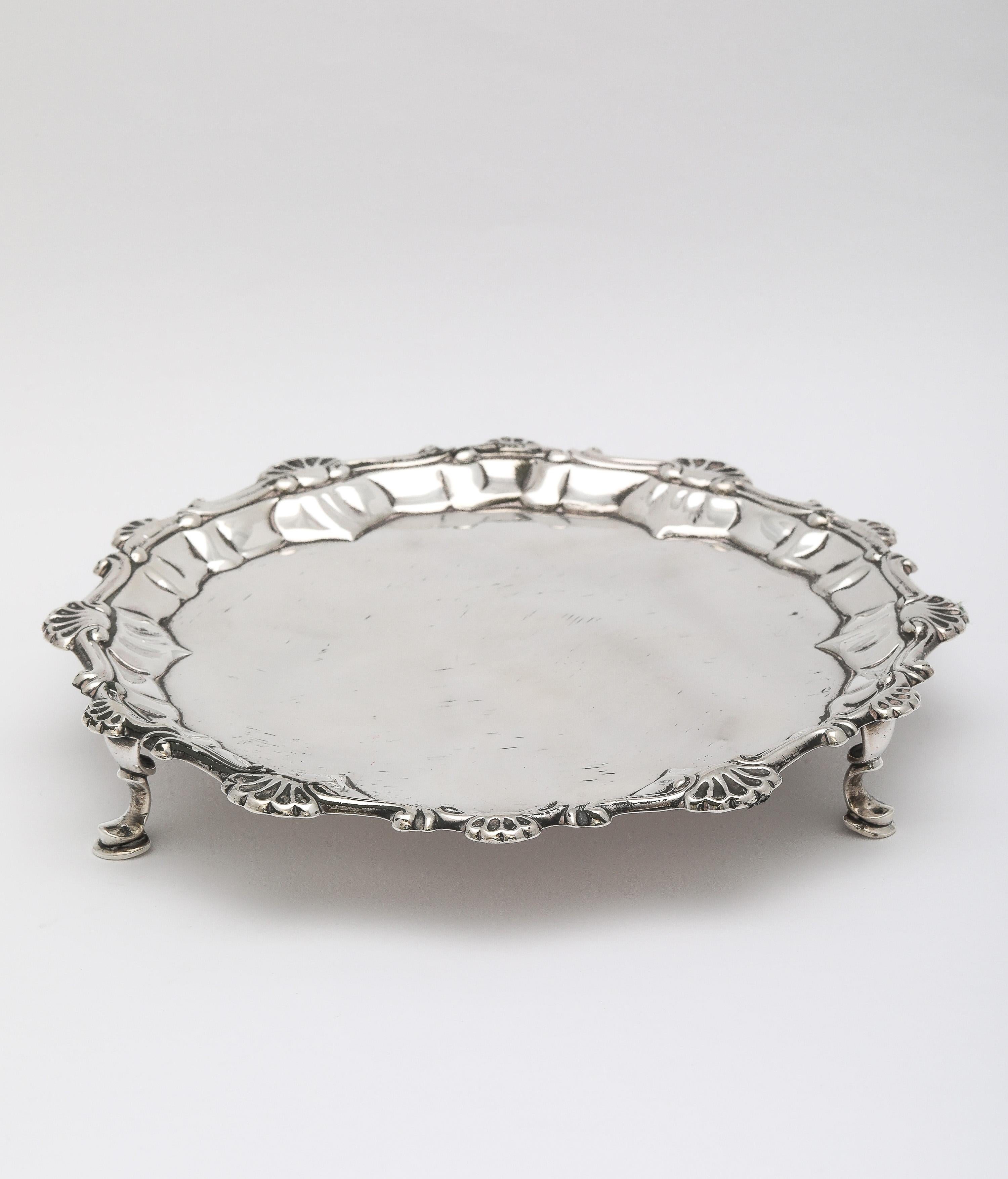 Sterling silver, George III Period, hoof-footed salver, London, England, year-hallmarked for 1765, Ebenezer Coker - maker. Scroll and shell designed border.  Measures almost 6 3/4 inches in diameter x 1 inch high. Weighs 6.280 troy ounces. There is
