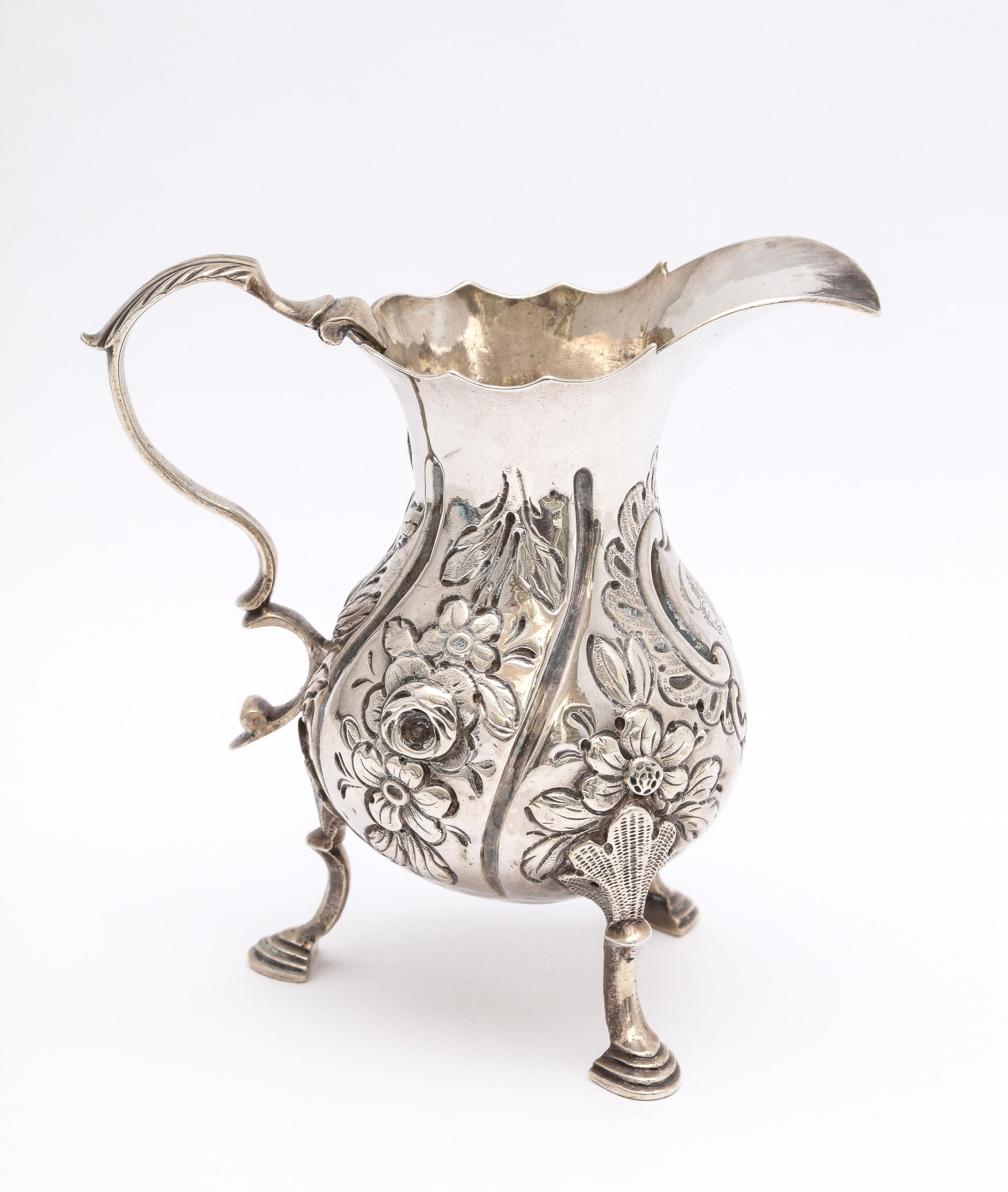Sterling silver, Georgian (George II), footed cream jug, London, year-hallmarked for 1759, John Muns - maker. Lovely chased work. Measures: 4 inches high (at highest point) x 4 inches wide (from edge of handle to edge of spout) x 2 inches diameter