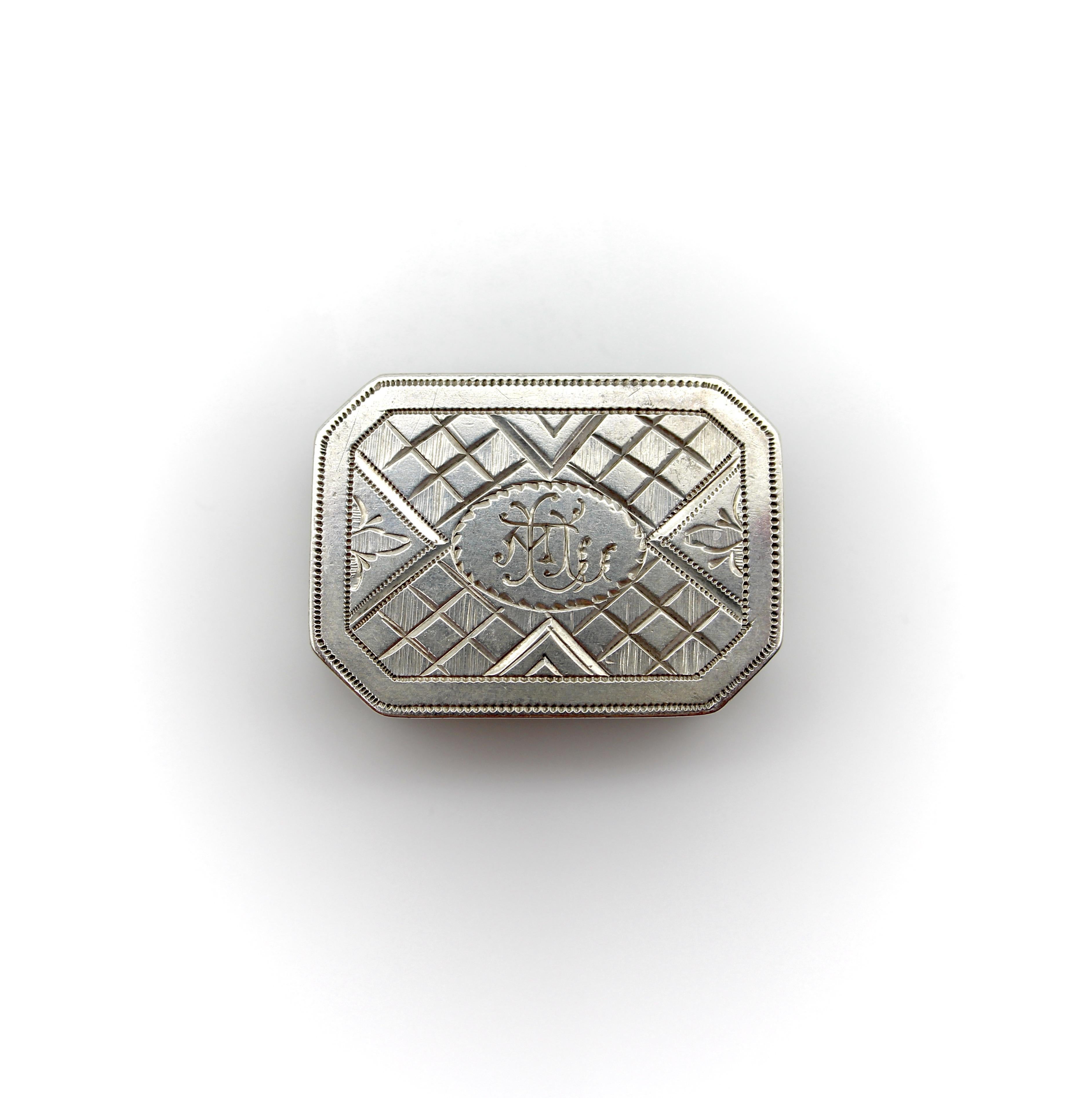 Circa 1816, this sterling silver vinaigrette is octagonal, with convex top and bottom lids, giving it a nice rounded shape. The top of the box is engraved with a latticework design, and the bottom of the vinaigrette is engraved with a flower that