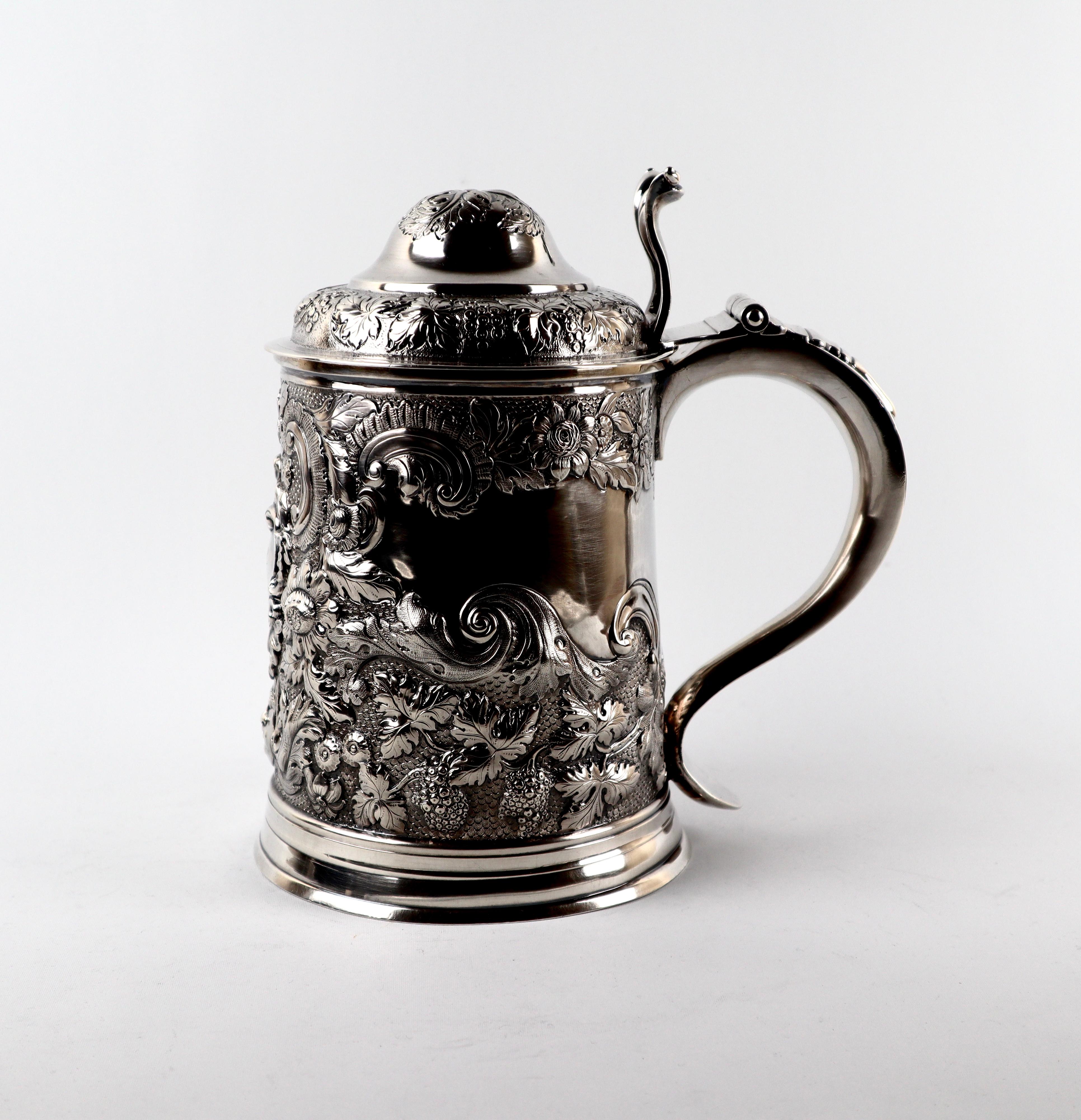 A rare antique Georgian Sterling silver lidded tankard dating dork the 18th century, with an S scroll handle with foliate thumb piece attached to a high domed cover.
Both body and cover are exquisitely embossed with impressive chased scroll leaf