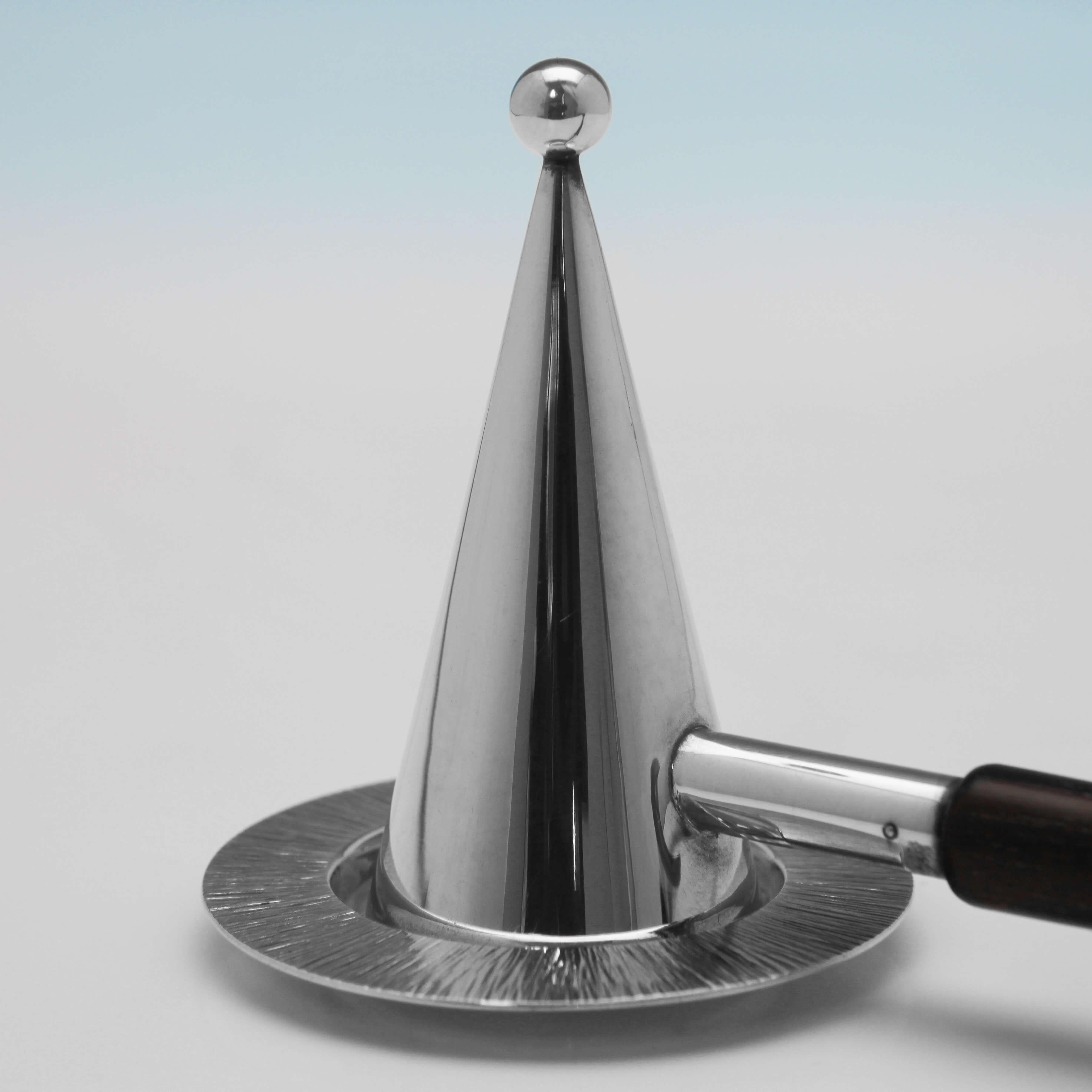 Hallmarked in London in 2000, this simple and elegant sterling silver candle snuffer and stand has a fruitwood handle and bark effect decoration. The candle snuffer was made by Gerald Benney and the stand was made by his son Simon Benney. The