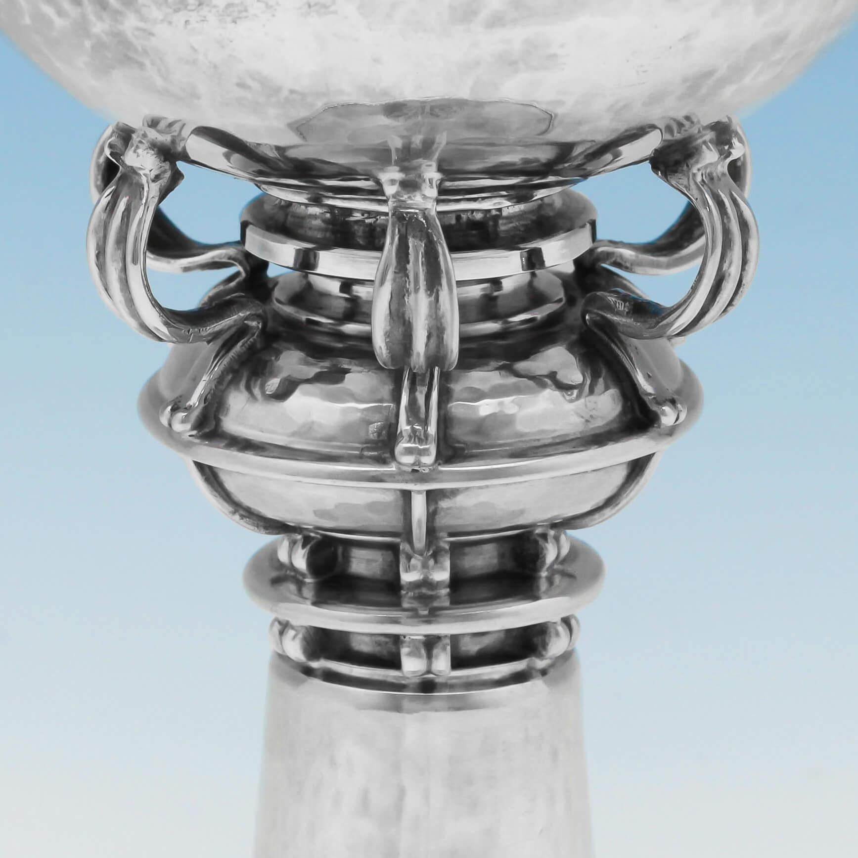 Hallmarked in London in 1920 by Omar Ramsden, this rare, striking, sterling silver goblet, is in the Arts & Crafts style, featuring a hand hammered finish, rope detailing, and an ornate scroll support knop. The goblet is chased with the initials of