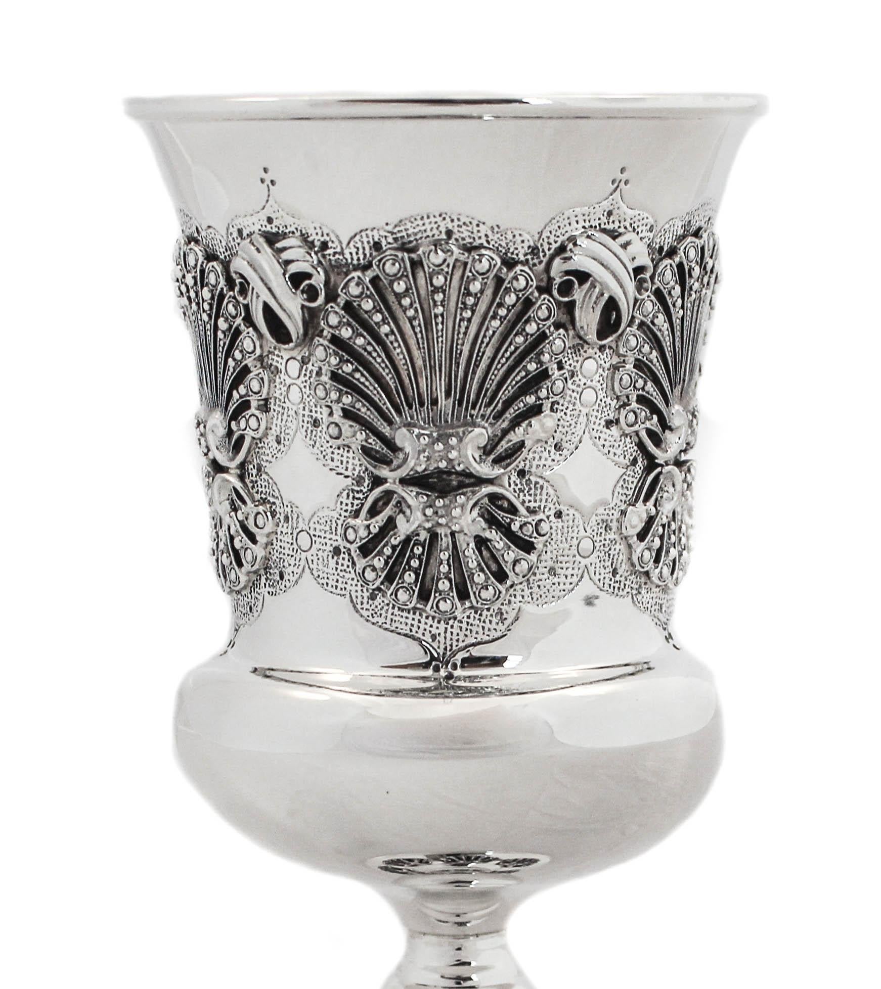 A beautiful sterling silver Kiddush cup (goblet) is being offered. The workmanship around the center and base is gorgeous! A shell-like design with a beaded motif in the middle.