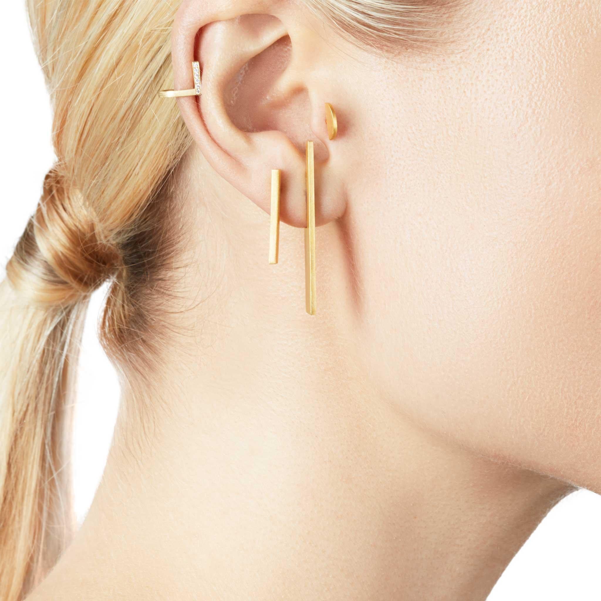 Die Collection'S Unfinishing Line strahlt mit ihren glatten Linien und Winkeln Minimalismus und Präzision aus. 
Detaillierte, perspektivische und flache Struktur mit gebürsteter Oberfläche. 
Lange perspektivische Ohrringe sind stilvoll, um mit jedem