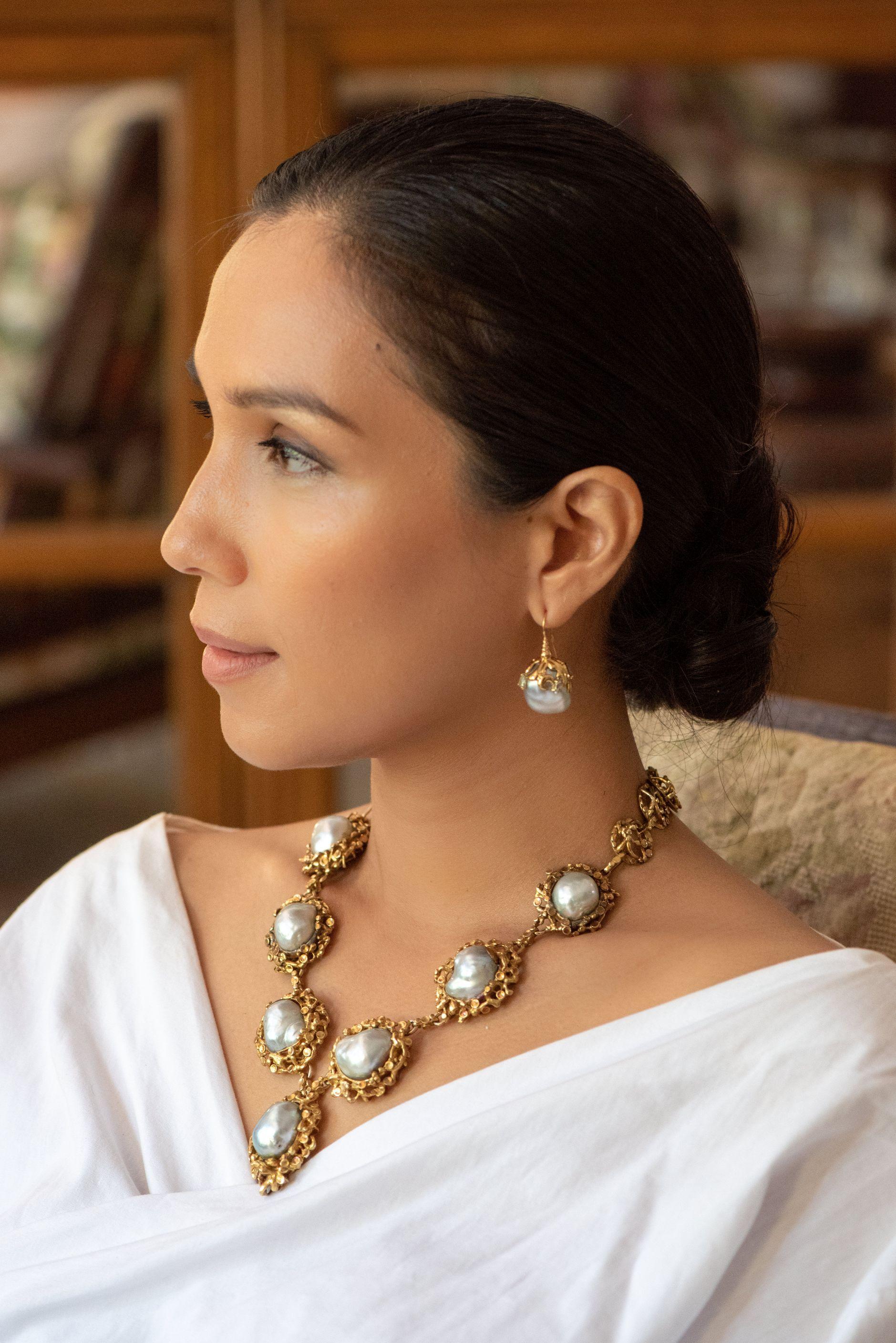 A magnificent sterling silver, 18 karat gold plated princess necklace featuring seven luminescent blue baroque south sea pearls nestling around a central medallion of 2.9 by 4 cm. 

The beautifully detailed work on the stone settings, as well as the