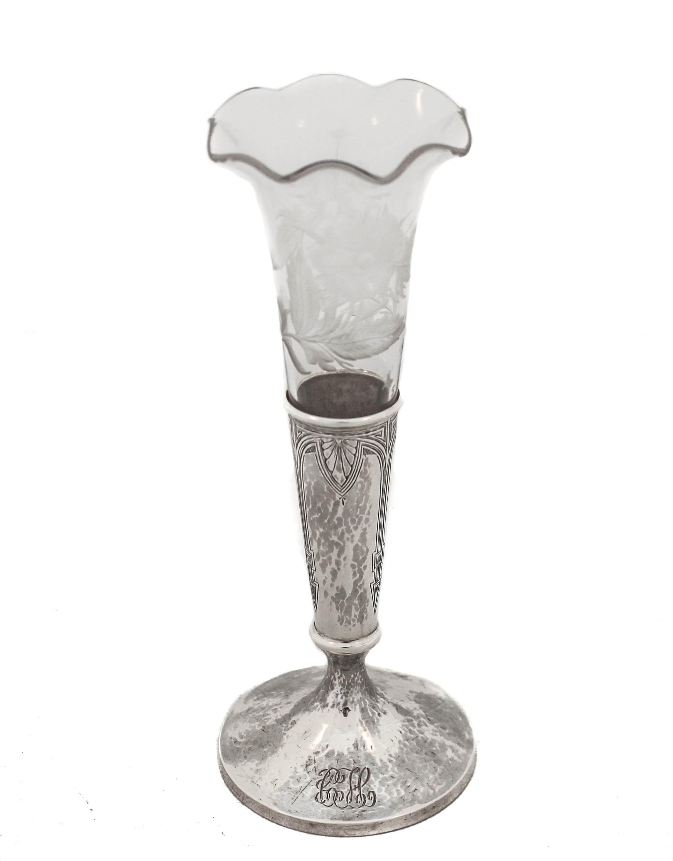 Being offered is a sterling silver bud vase with the original glass liner.  The silver vase is designed in the Art Deco style with symmetrical motifs.  The glass liner is scalloped and has acid-etched flowers and leaves all around.  This piece would