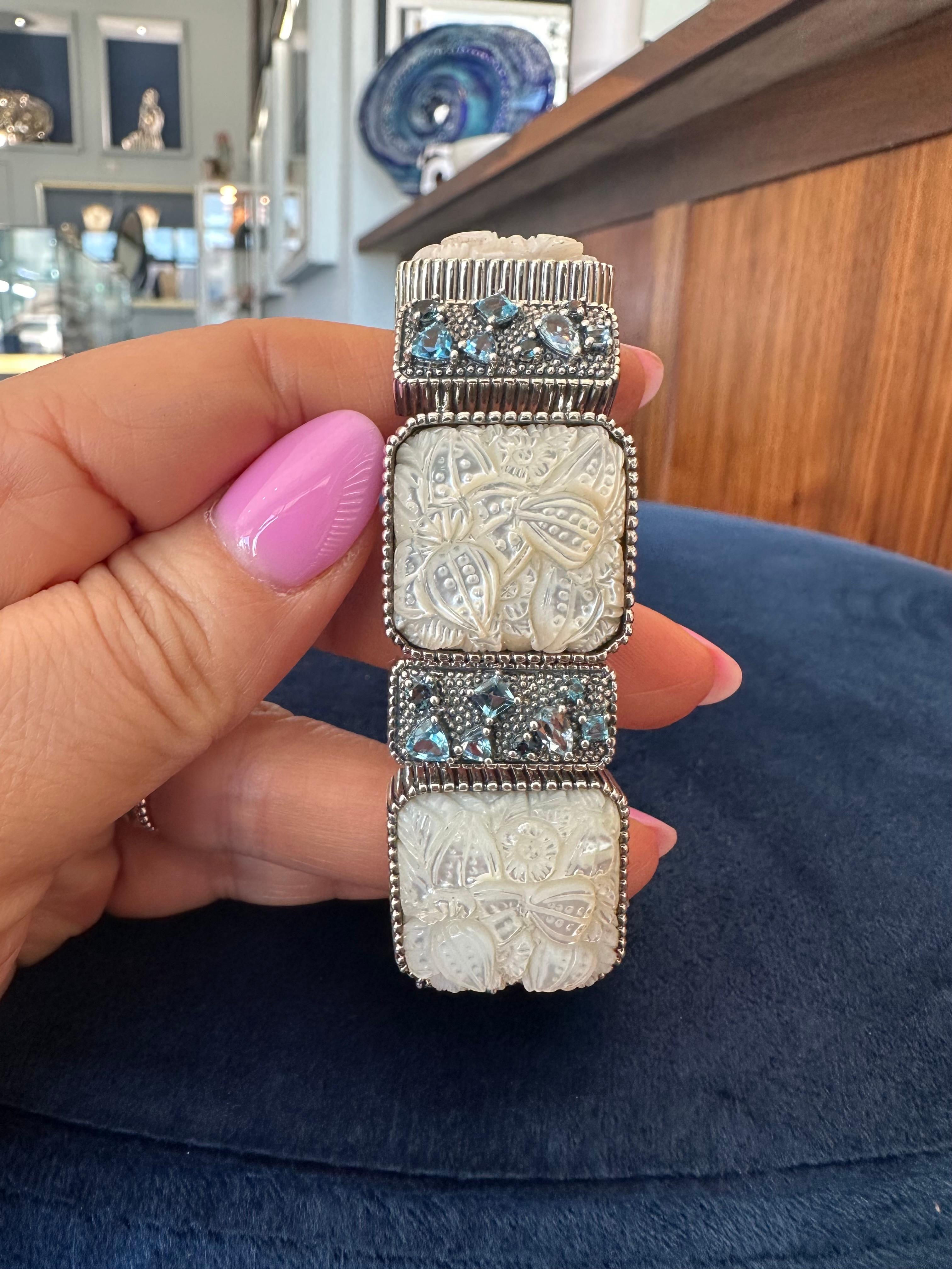 This elegant Stephen Dweck bracelet is a stunning example of artisanal craftsmanship. Crafted from premium sterling silver, this exquisite piece features hand-carved mother of pearl, which adds a layer of sophistication and natural beauty. The