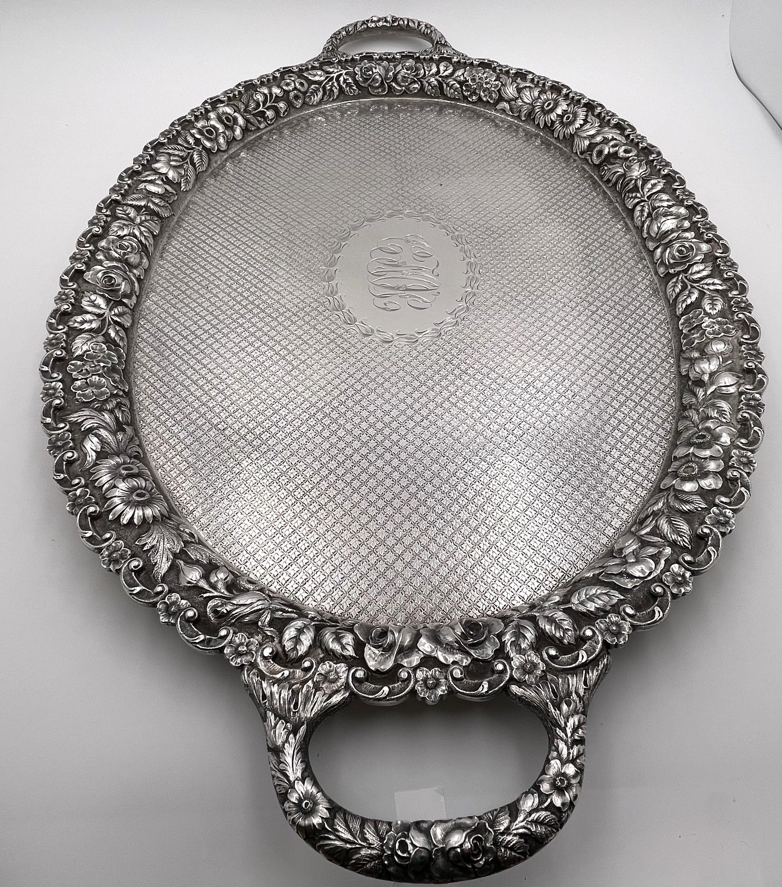 Hand chased sterling silver two-handled tray in Rose pattern and in repousse design, with beautifully diapered at the center. It measures 28 3/4'' from handle to handle (24'' excluding the handles) by 17 3/4'' in width by 1 1/2'' in height, weighs