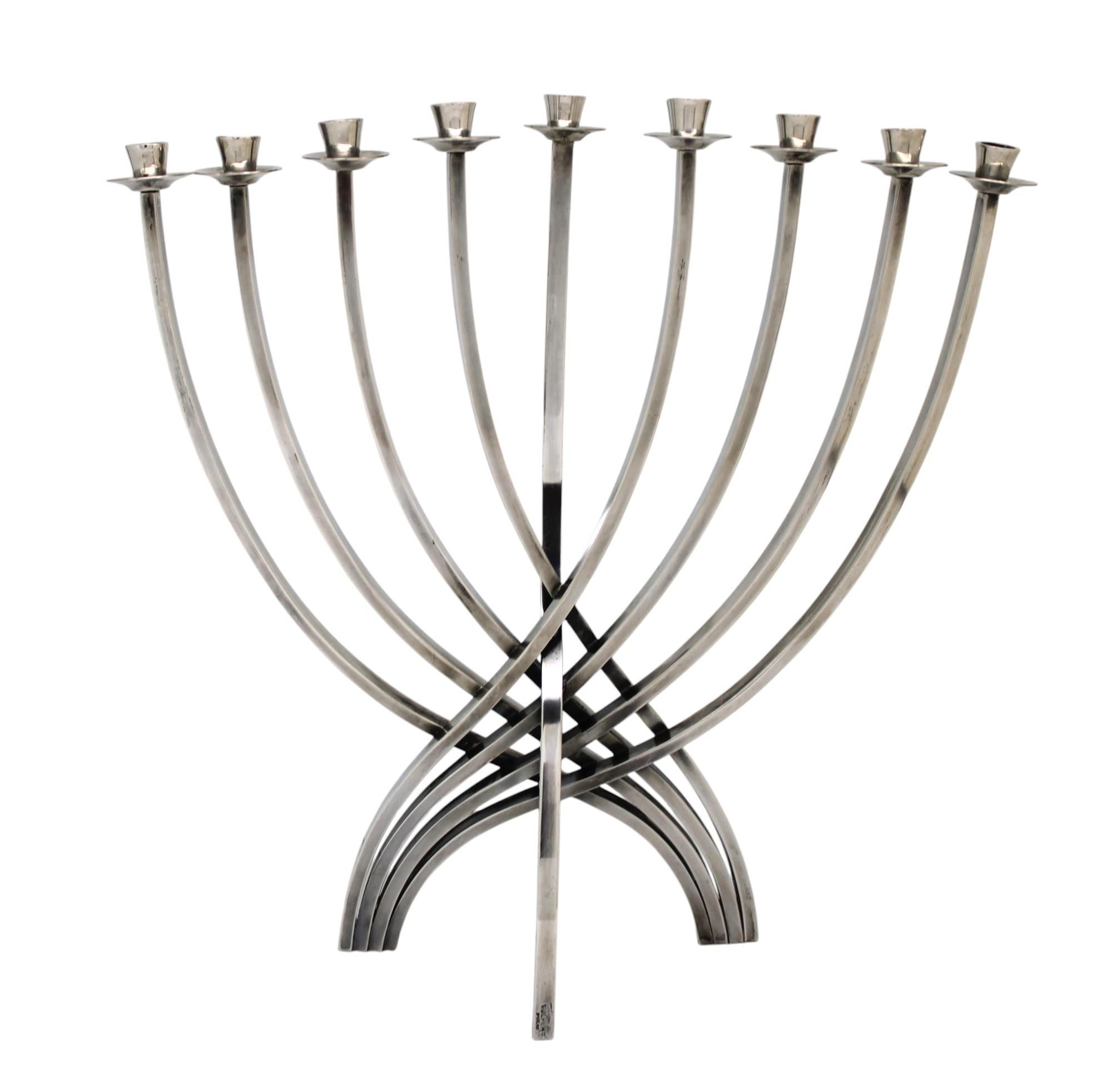 Esta llamativa menorá de Hanukkah, diseñada por Ludwig Yehuda Wolpert, personifica su característica estética modernista y su ingenio geométrico. Fabricada en plata de ley, la menorá presenta una estructura limpia y elegante con brazos grácilmente