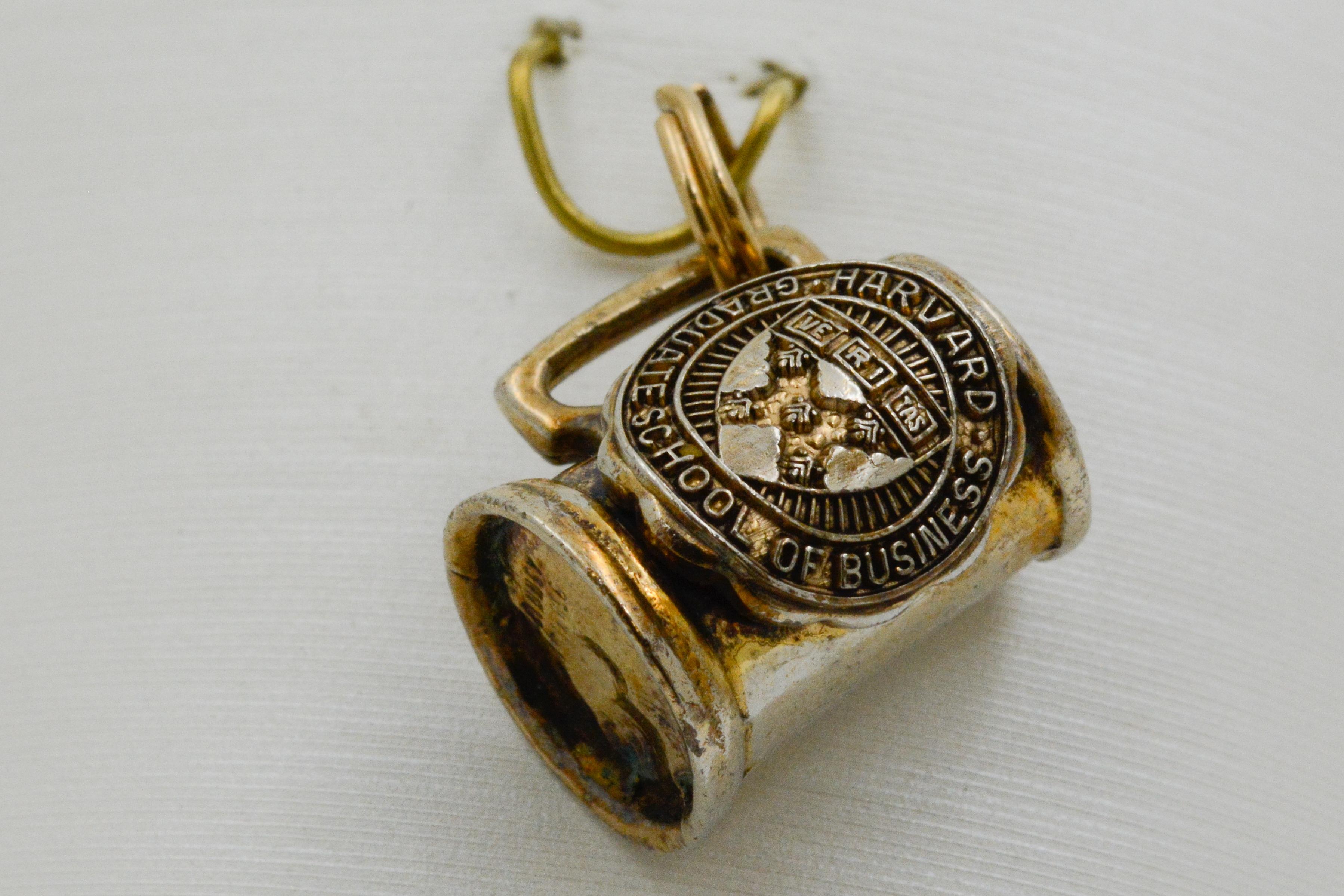 This vintage sterling silver stein charm features the crest of Harvard Business school for graduates. On the crest the words 