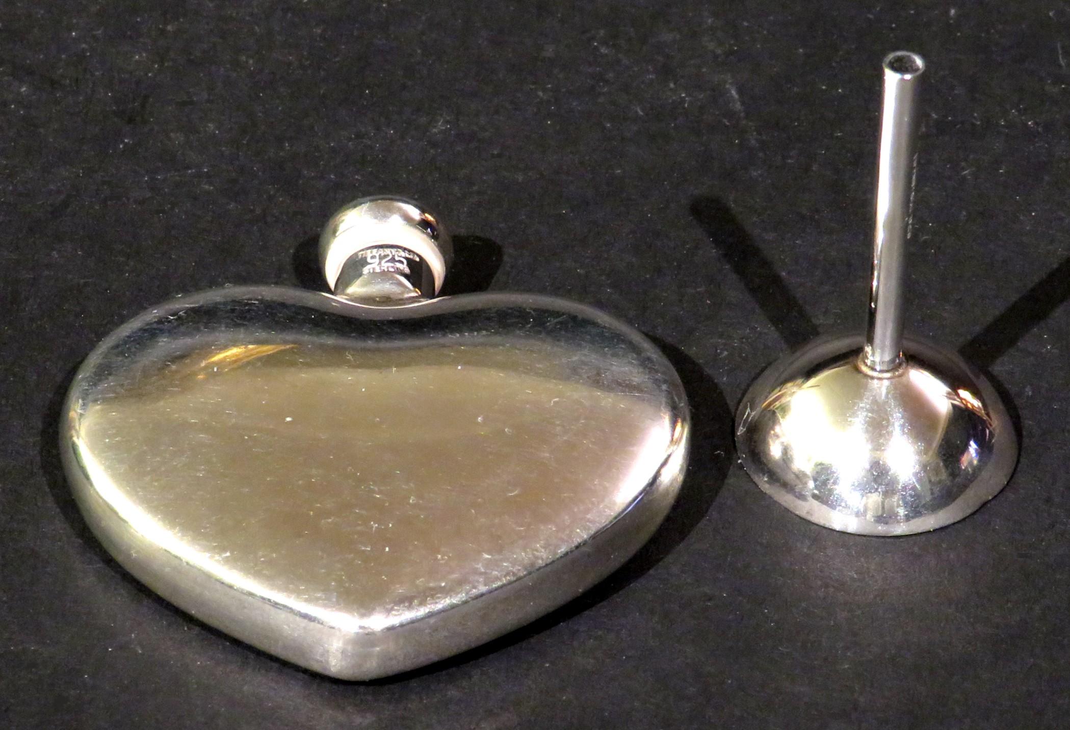 The beautiful heart shaped sterling silver body fitted with a screw-on cap bearing stamped marks 'Tiffany & Co. Sterling 925’, one side monogrammed with initials. 
Together with its original sterling silver funnel, also marked Tiffany & Co. 925,