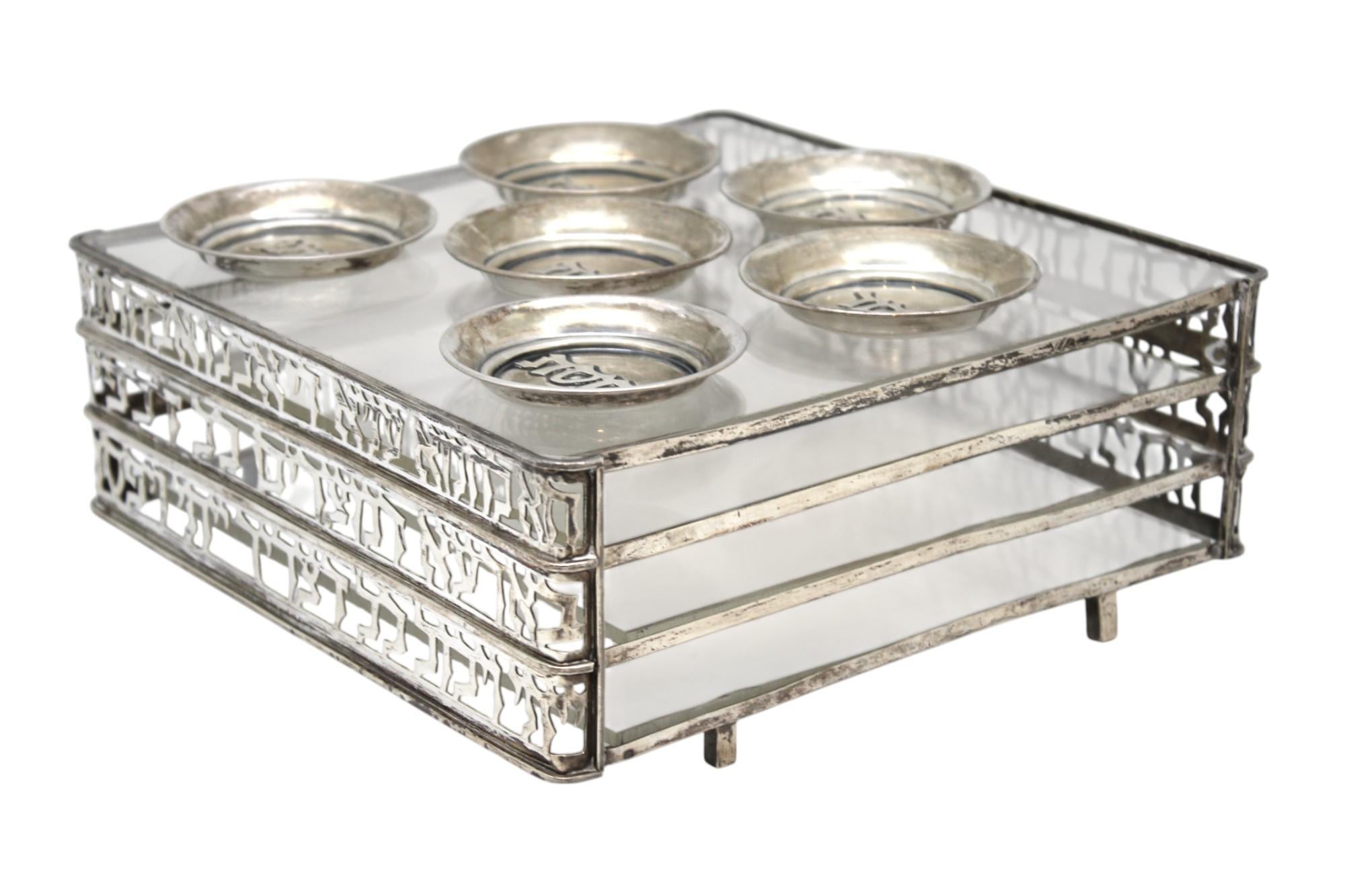 Esempio straordinario di design ebraico israeliano della metà del XX secolo, questo compendio modernista per la Pasqua ebraica degli anni '50 combina il simbolismo tradizionale con un'estetica elegante e architettonica in argento sterling e acrilico