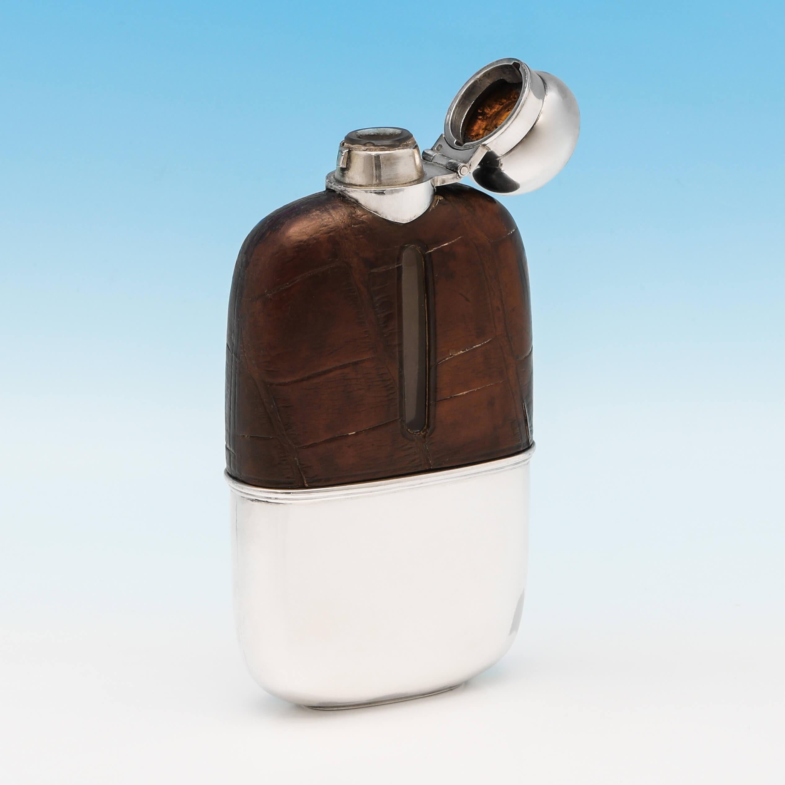 Hallmarked in Sheffield in 1931 by G. & J. W. Hawksley Ltd., this handsome, sterling silver hip flask, features a crocodile leather bound upper body, a bayonet cap, and a removable silver cup. The hip flask measures 5.5