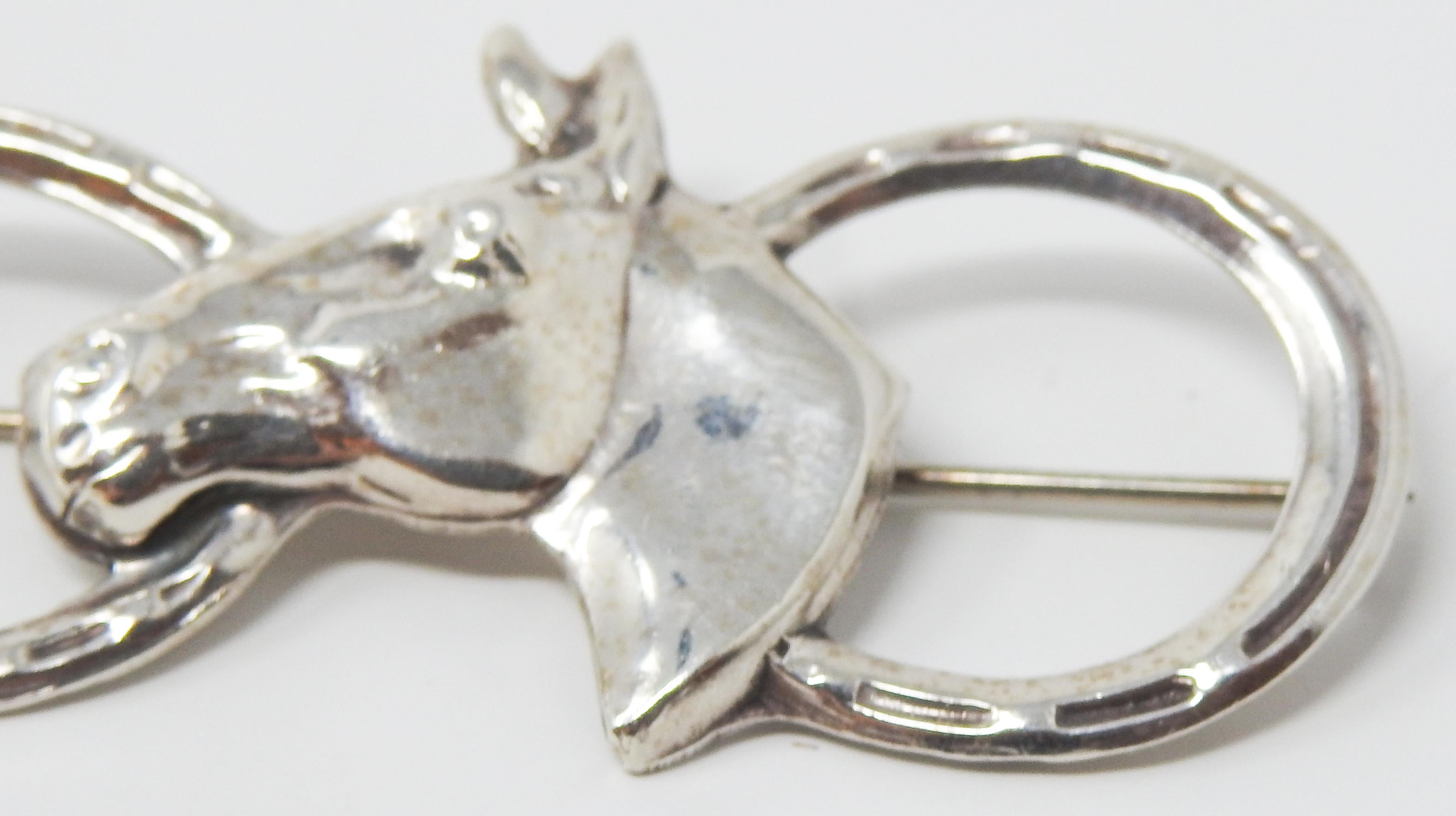 Offering this handsome sterling silver horse shoes and horse head brooch. There are two horse shoes on the outsides with a horse head in the center. The horse head is marked sterling.