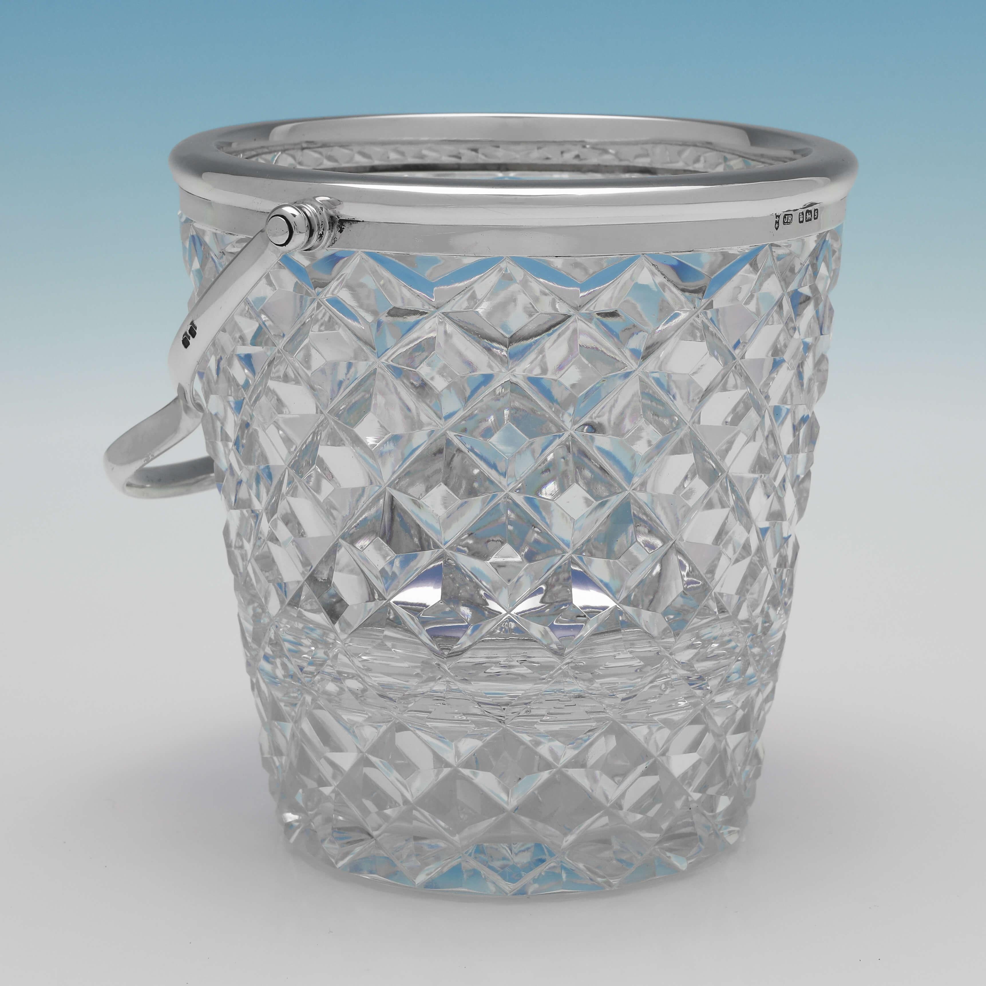 Hallmarked in Sheffield in 1910 by John Round & Son Ltd., this attractive, Edwardian, Antique Glass & Sterling Silver Ice Bucket, features a stylish cut glass body, silver rim and handle, and a removable silver ice strainer. The ice bucket measures