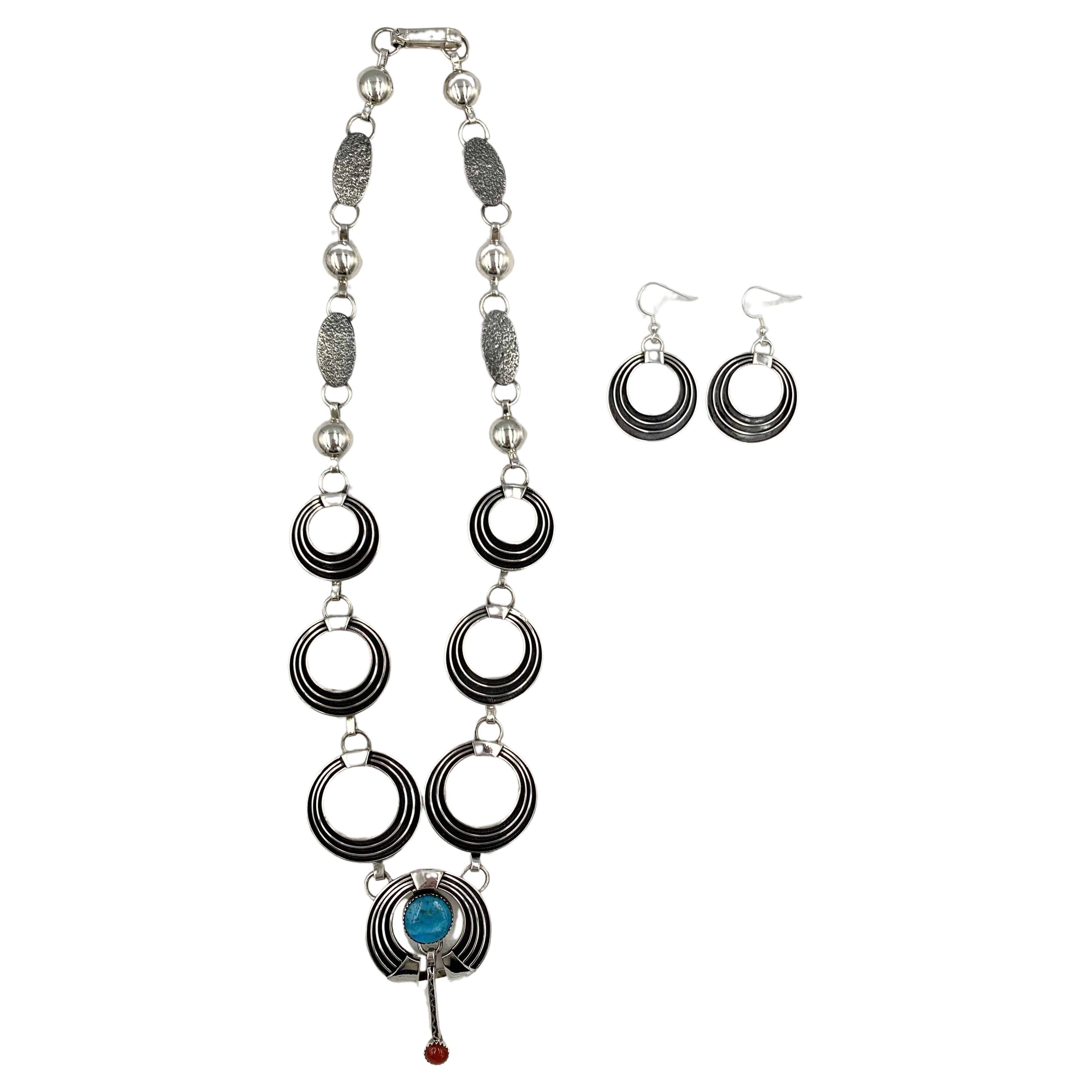 Sterling silver and inlay necklace and earrings set by Navajo silversmith Jack Tom. The pendant has turquoise and coral.

Tom's signature design is sleek and elegant with refined oxidized ridges against bright sterling silver. The contrast of