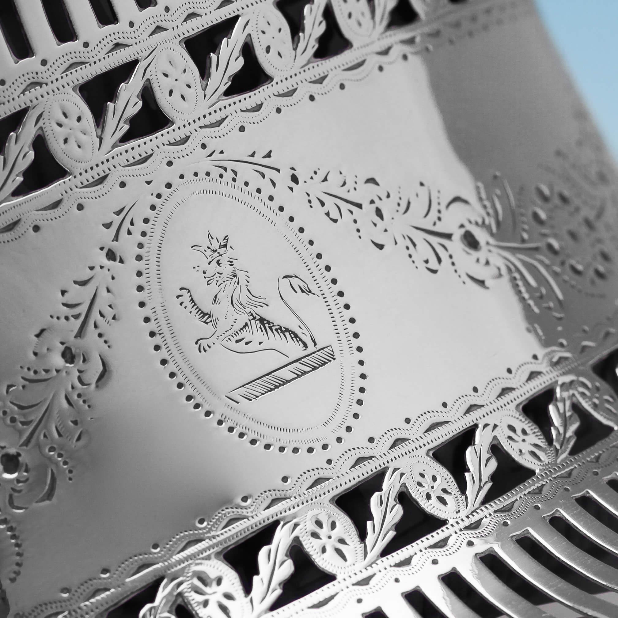 Hallmarked in Dublin in 1784, possibly by John Lloyd, this wonderful, George III, antique sterling silver dish ring, features delicate pierced and engraved decoration, a blue glass liner, and an engraved crest to the cartouche. The dish ring