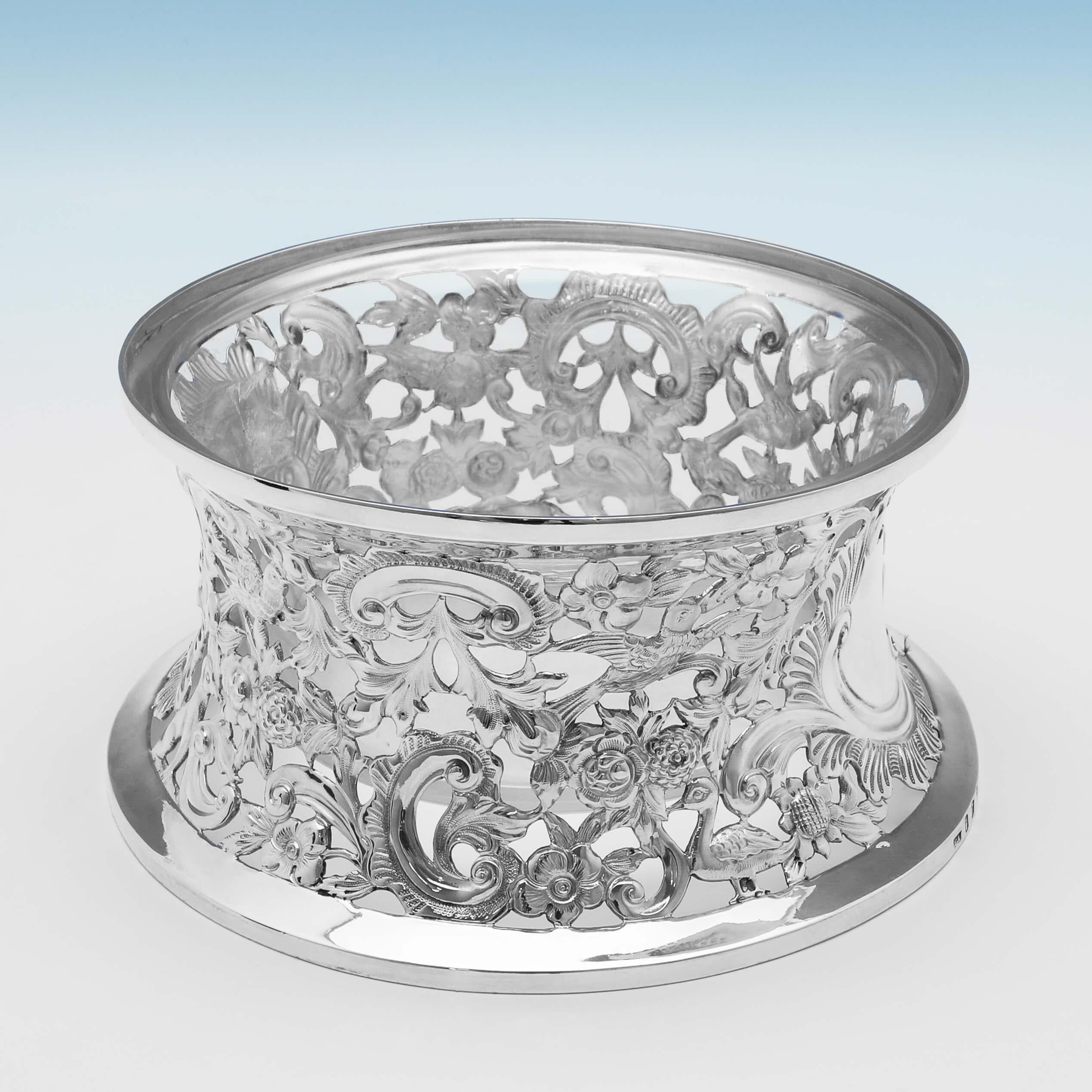 Hallmarked in Dublin in 1895 by Charles Langley, this charming, antique sterling silver dish ring, features chased and pierced decoration depicting flowers, leaves, birds, dogs and other animals, and a clear glass liner. The dish ring measures: 8