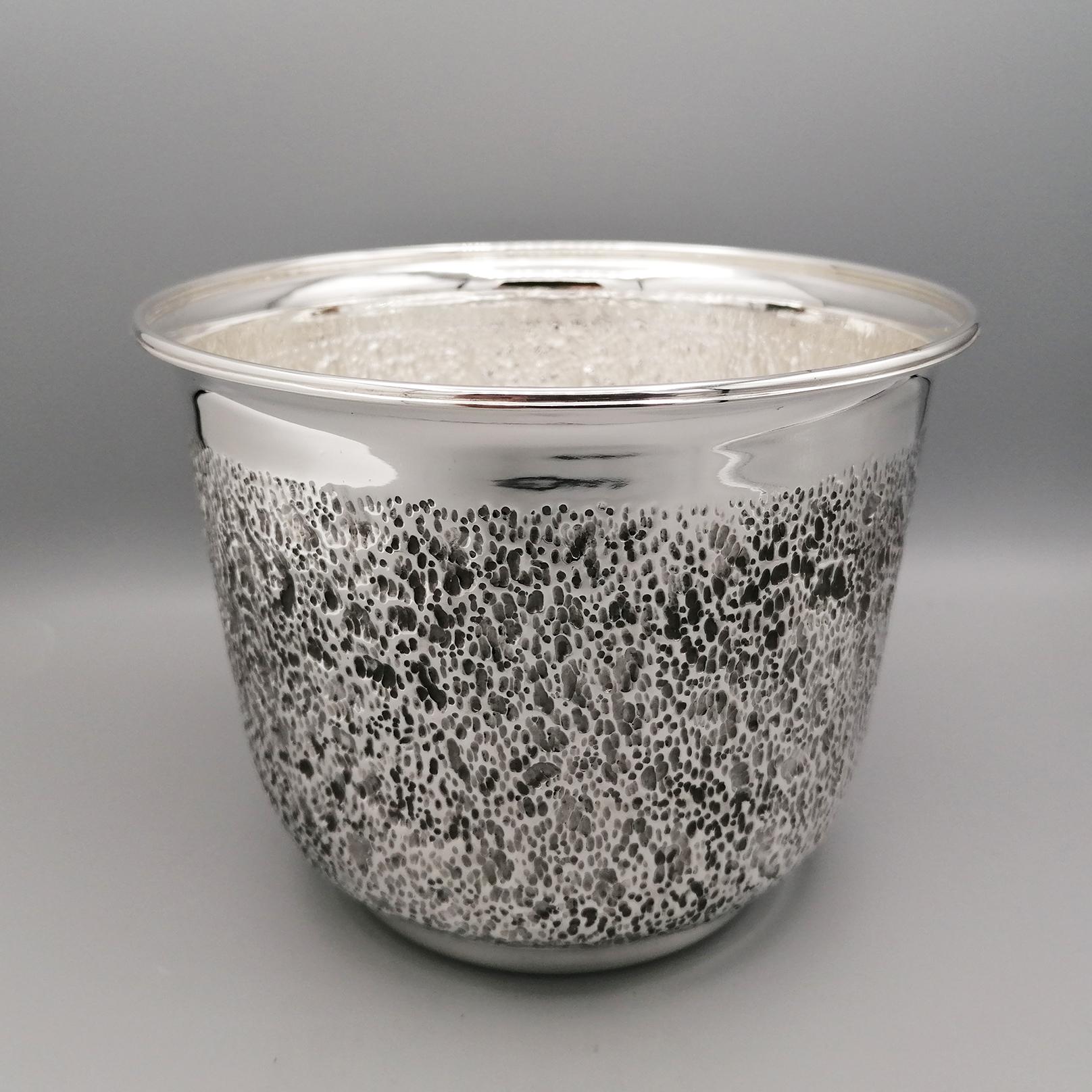 Round Flower Cachepot in Solid Sterling Silver.
Made entirely by hand, it has been finely embossed and chiseled on the central body giving it the design of a rough or rock wall.
This workmanship is interspersed with shiny parts on the upper and