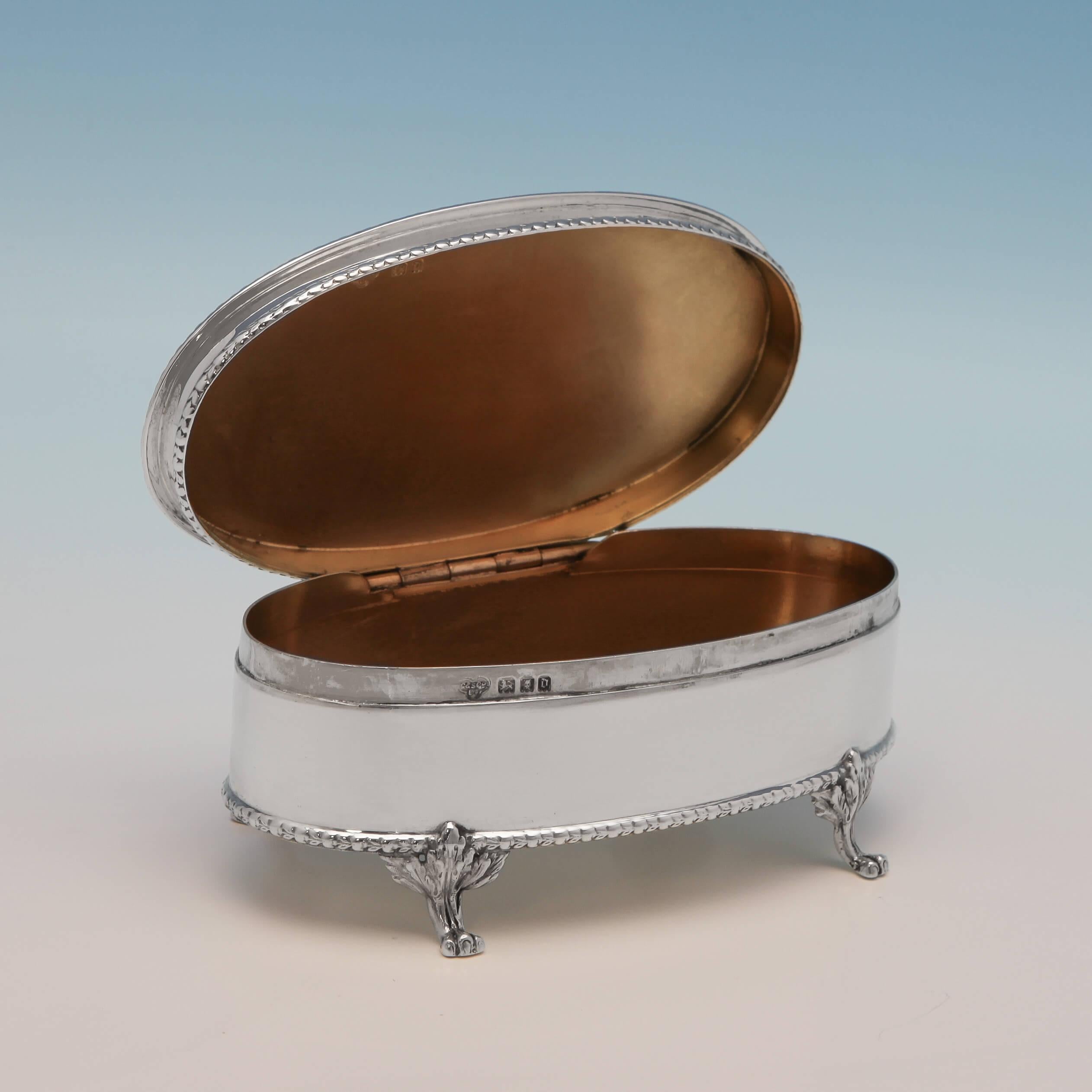 Hallmarked in London in 1919 by Goldsmiths and Silversmiths Co. This refined sterling silver jewellery box features an oval body with rope borders, a gilt interior, and stands on four paw feet. The jewellery box measures: 5