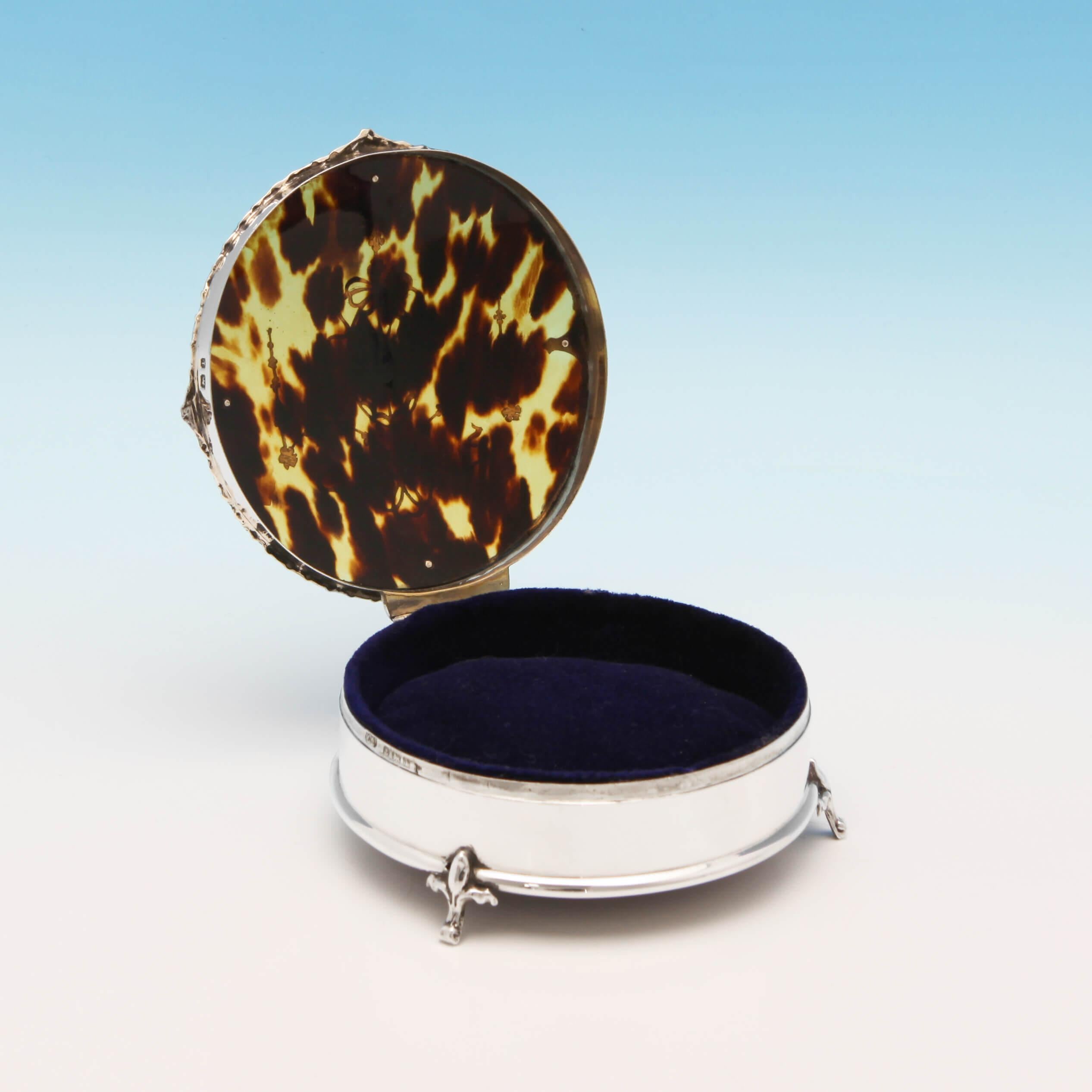 Hallmarked in Birmingham, in 1910, by Mappin & Webb, this pretty, George V, antique, sterling silver jewelry box, stands on three feet, and features a tortoiseshell lid with inlaid silver decoration, and a blue velvet lining. The jewelry box