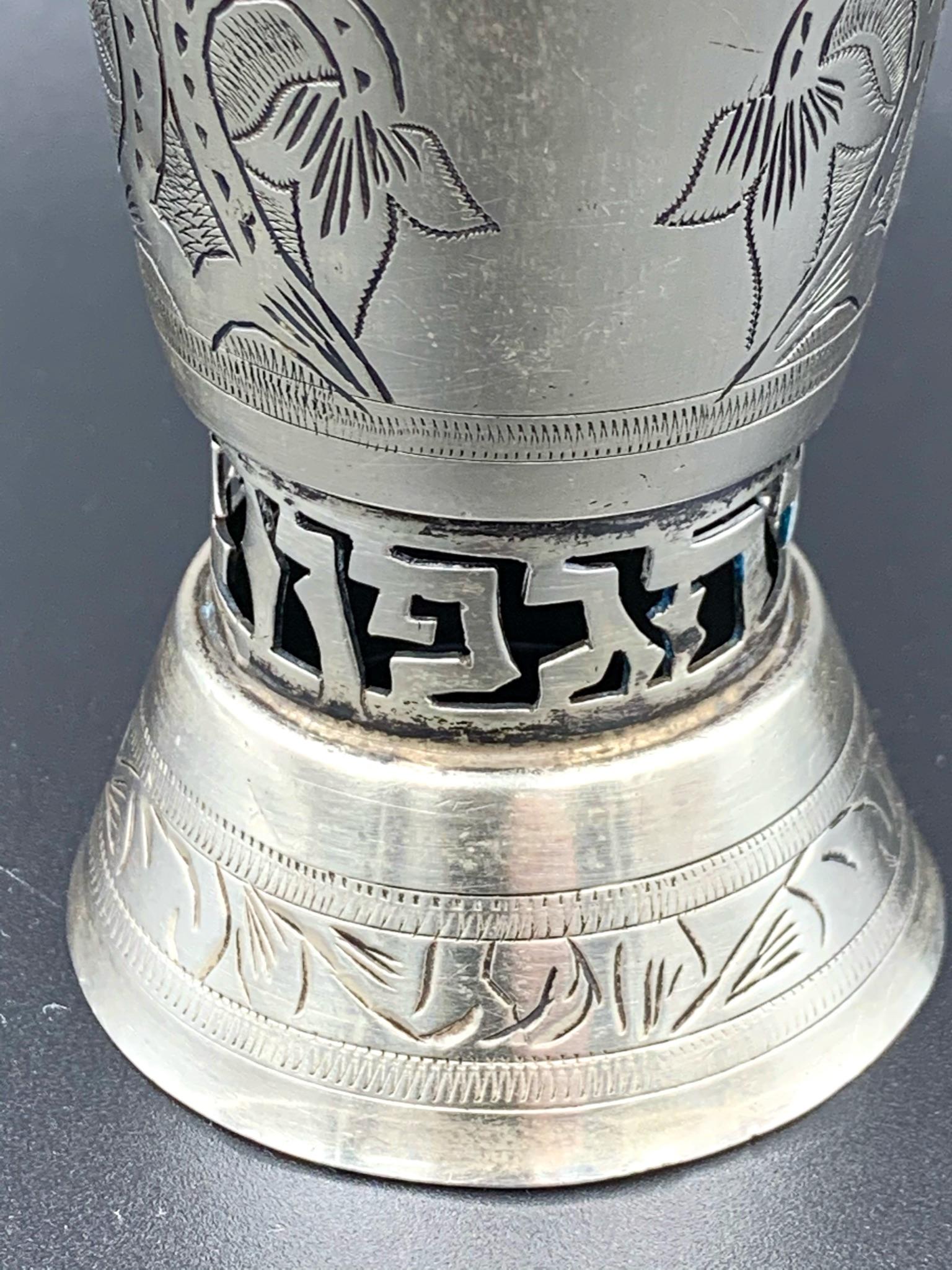 Handmade sterling silver marked Kiddush cup featuring an engraved design and cut out hebrew letters at bottom. It is 4.62